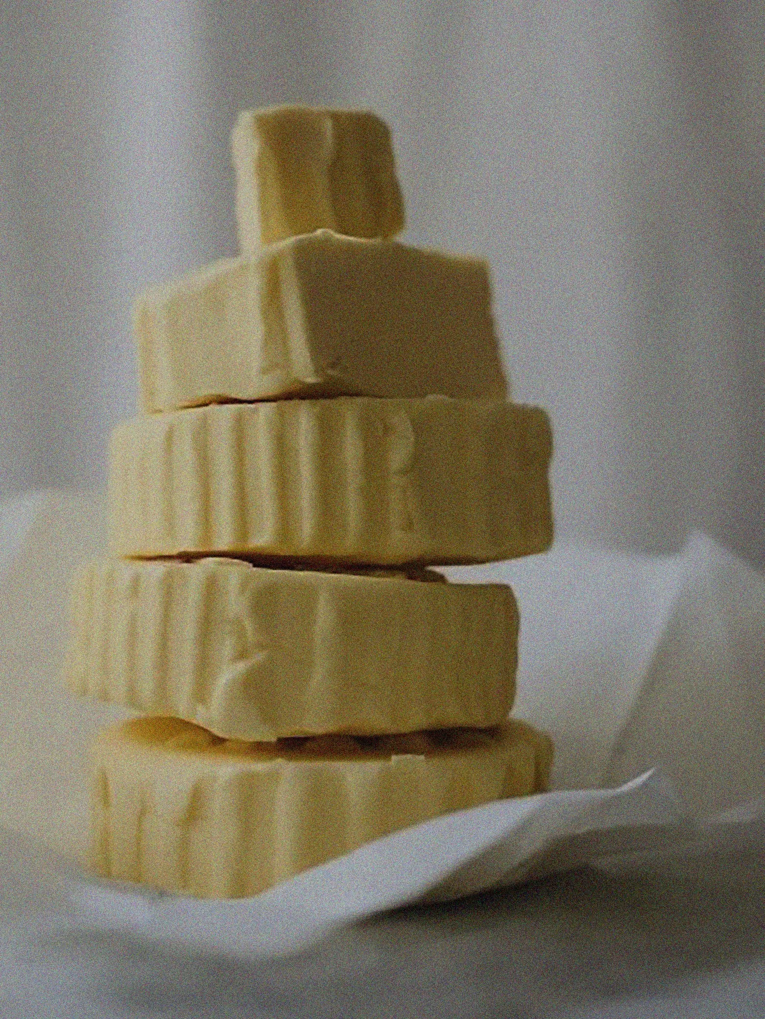 Close-up of several stacked pieces of yellow cheese on a white dish.