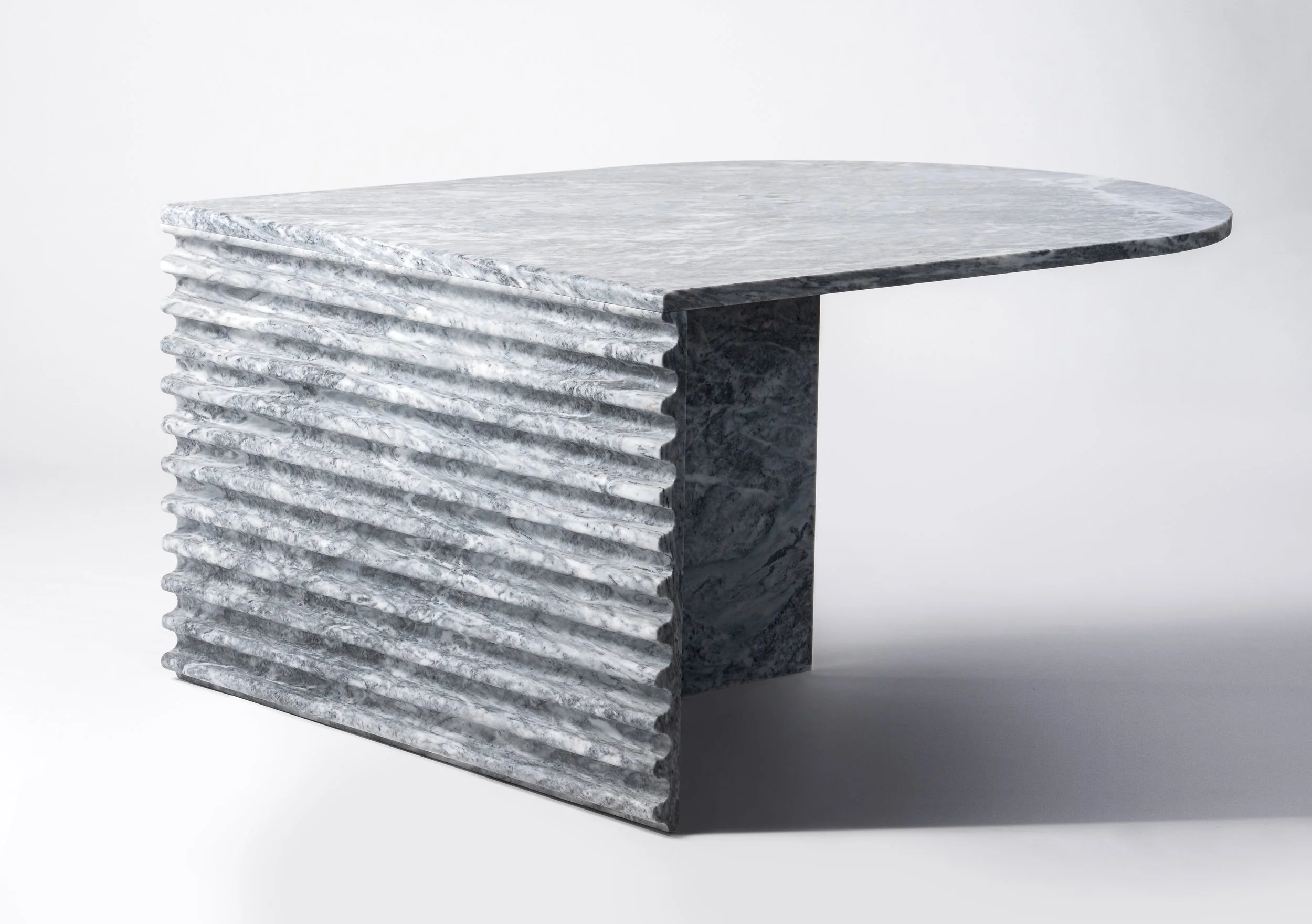 A modern desk made of white and gray marble with a textured, ribbed side panel and a smooth, flat top.