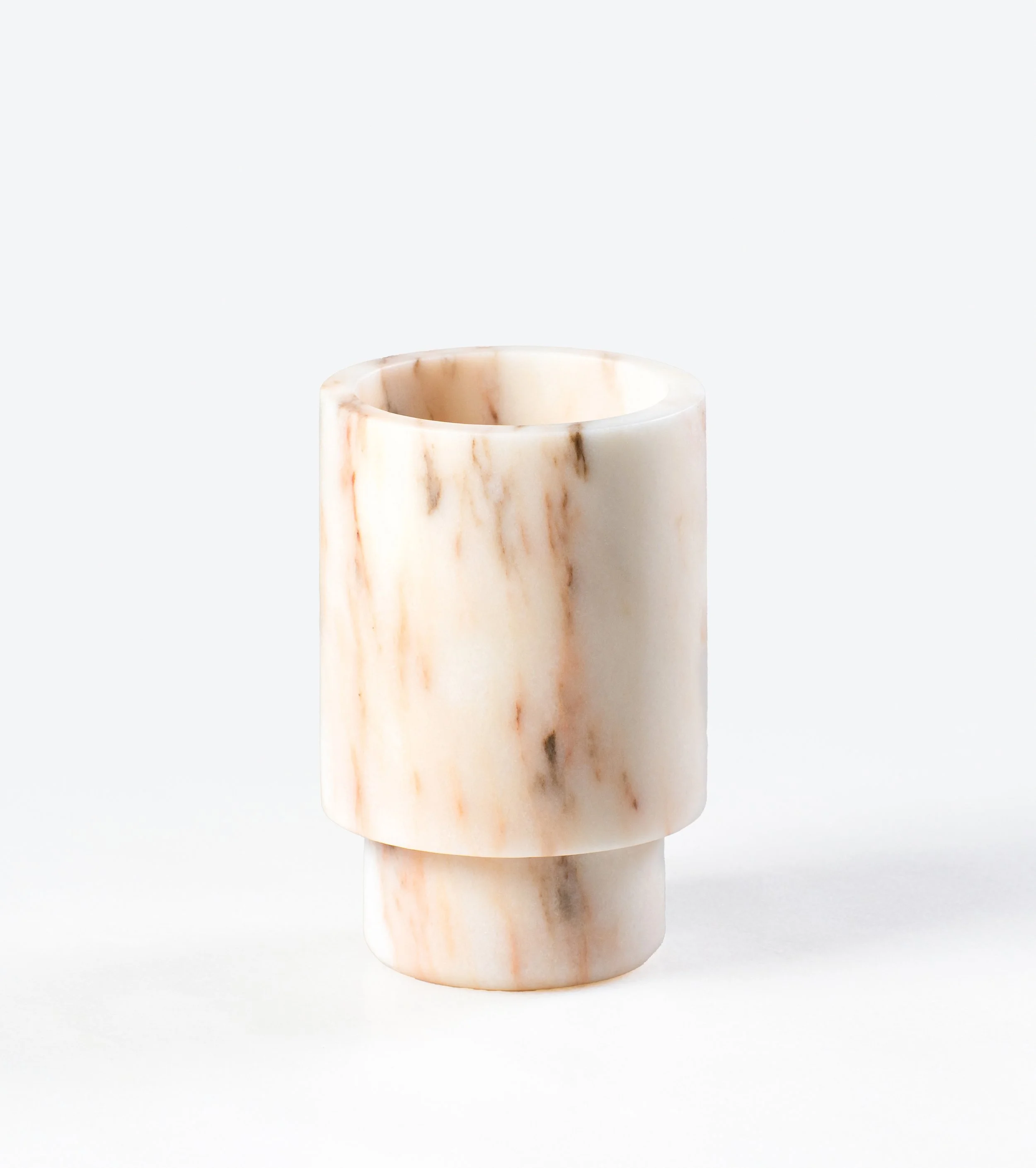 Close-up of a cylindrical marble object with brown and orange veining, set against a white background.