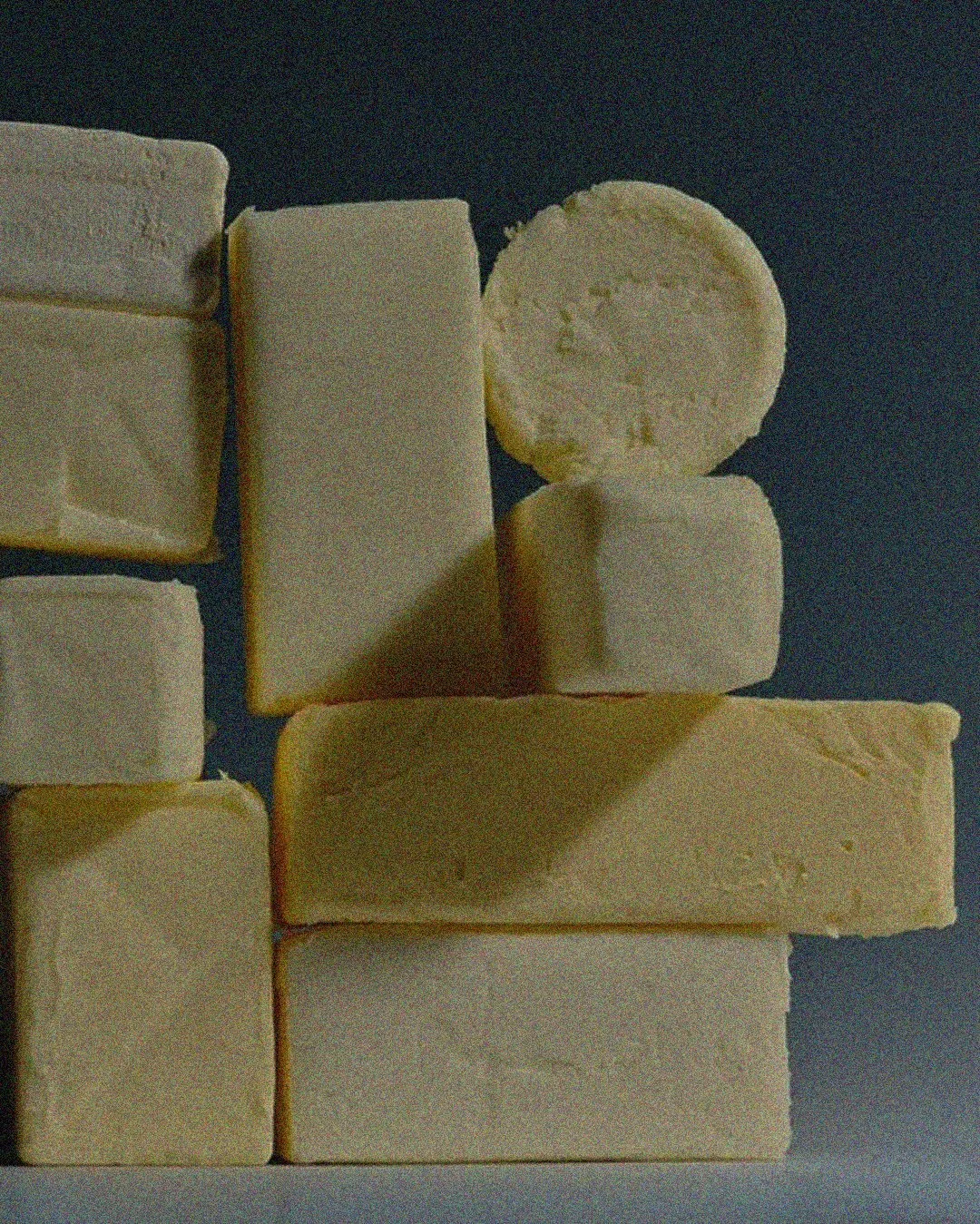 Slices of butter arranged on a dark surface.