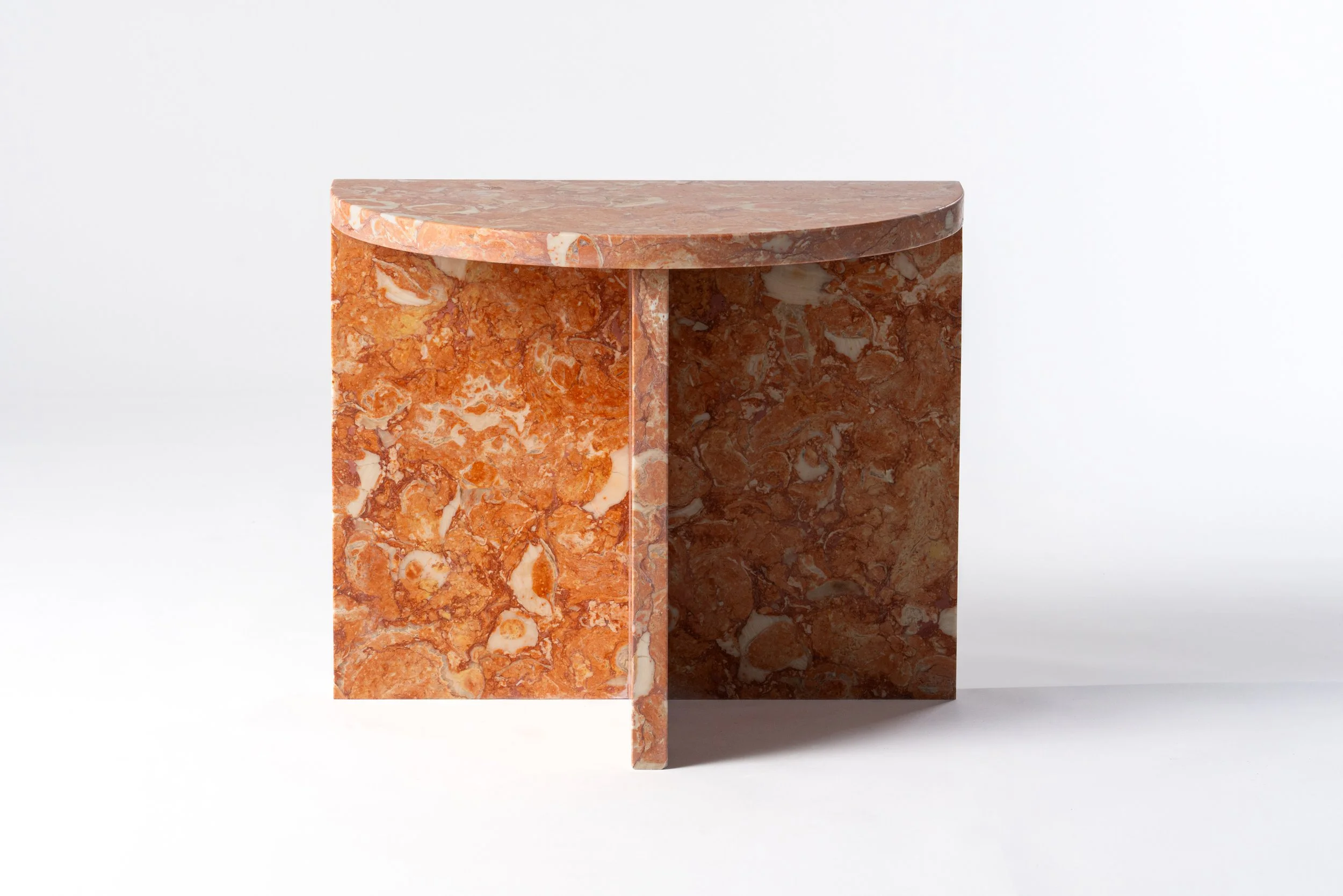 A modern, minimalist marble side table with a half-circle shaped top and rectangular sides, made of orange and white marbled stone.