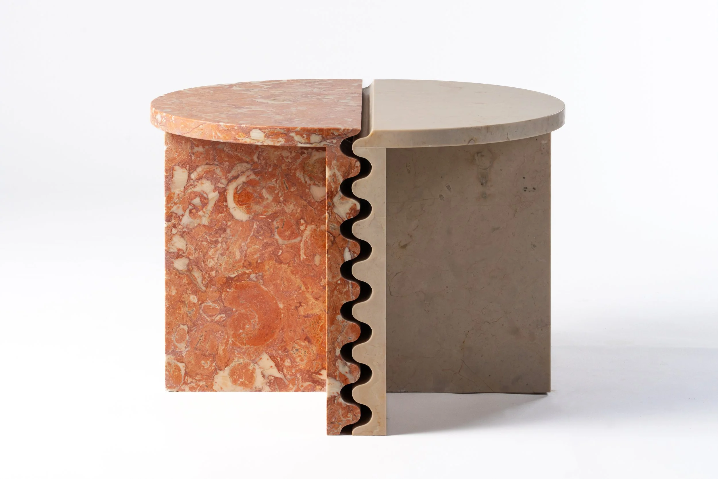 A cross-section of two different types of marble with a saw cut on the right side showing layered patterns in shades of pink, orange, cream, and beige.