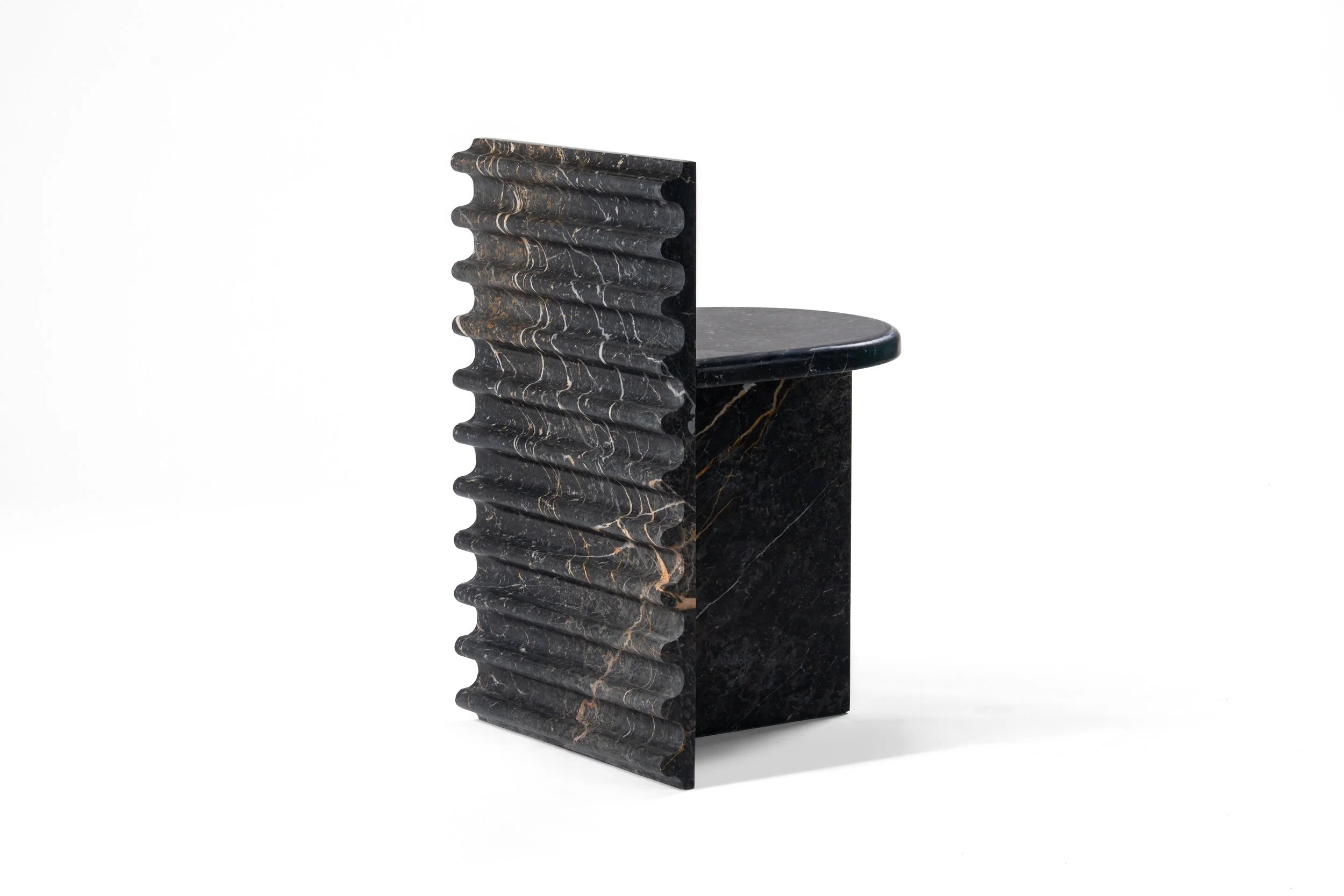Black marble sculpture with a wavy side panel and a flat, round top, set against a white background.