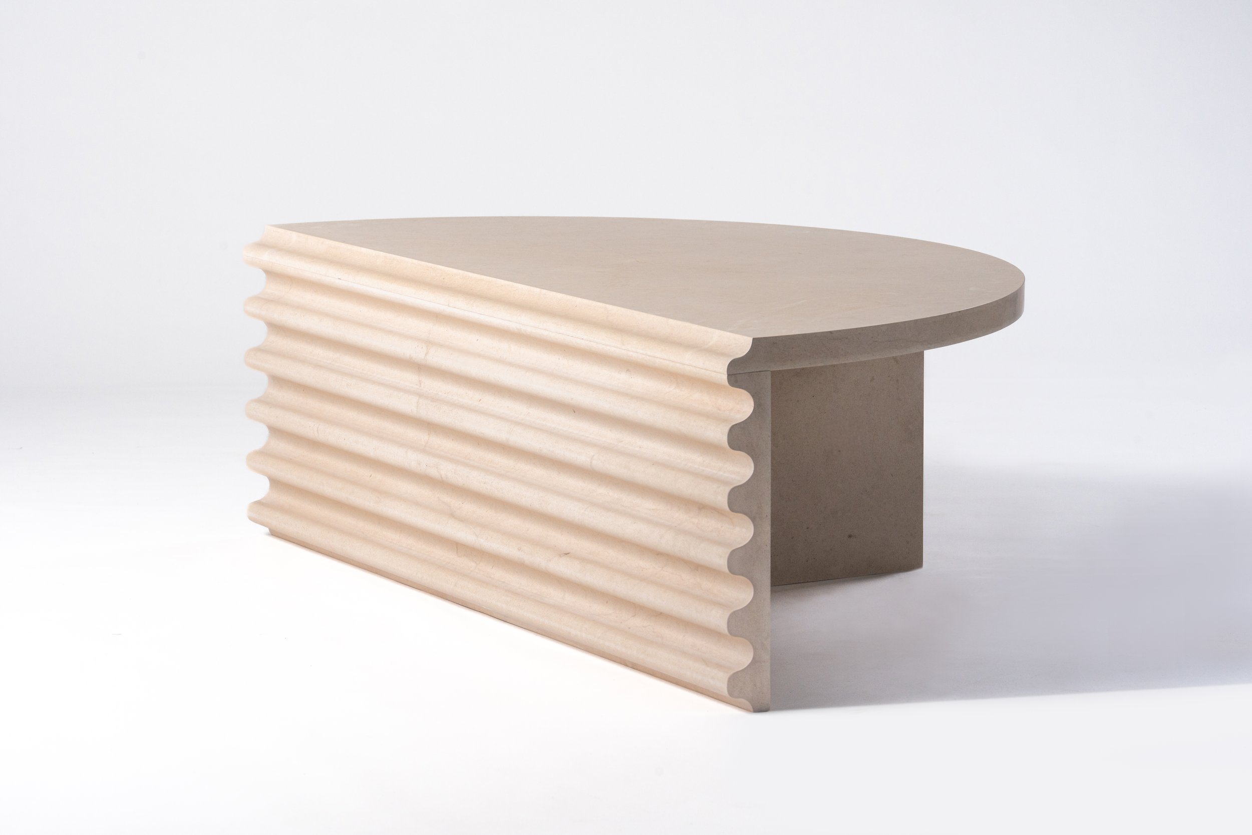 A modern, abstract sculpture made of layered, cream-colored material with a smooth, curved top and textured sides, set against a plain white background.