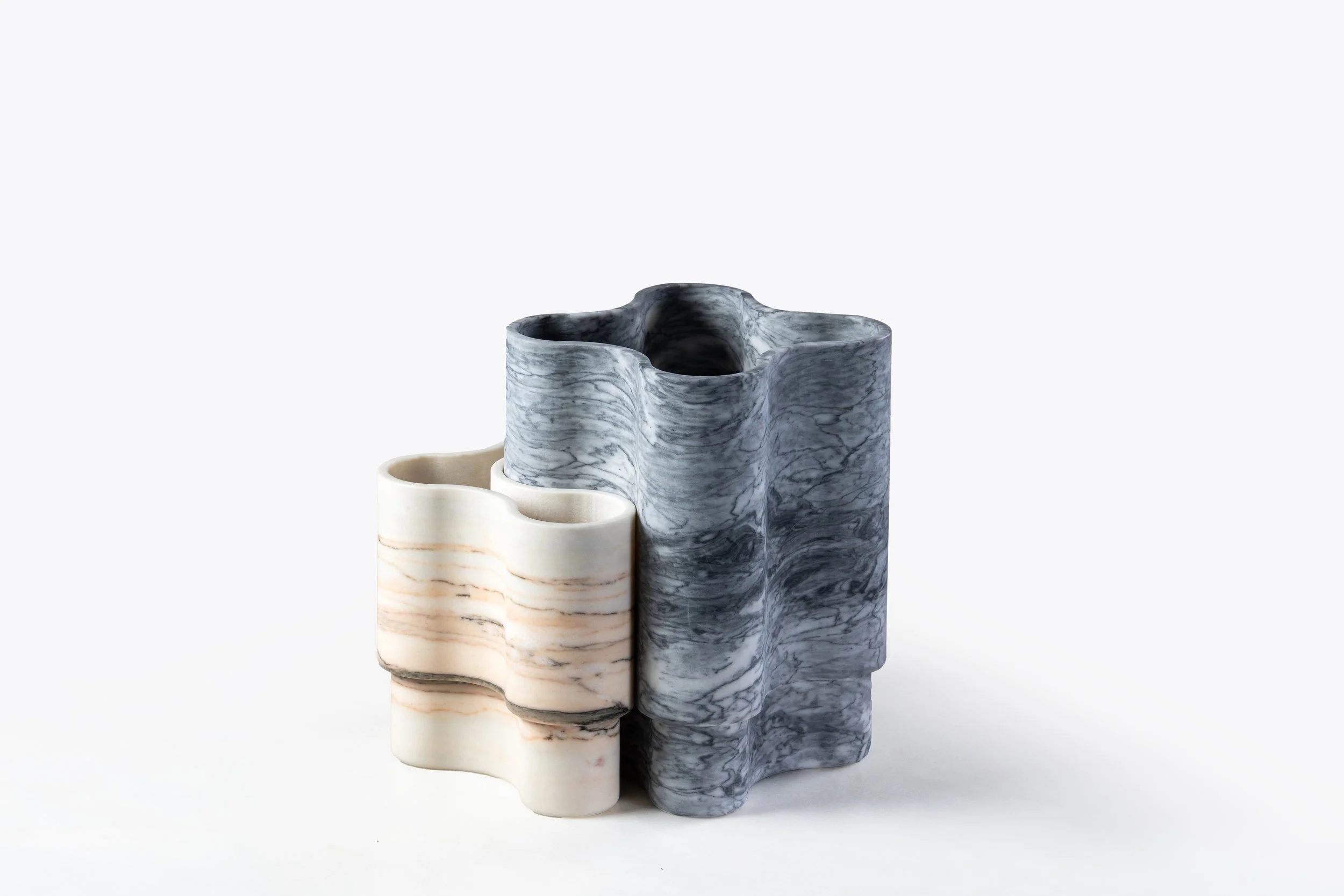Three decorative marble vases in different colors and patterns, with the smallest in a beige and cream marble, the medium in a light gray marble, and the tallest in a dark gray and black marble, all positioned against a plain white background.