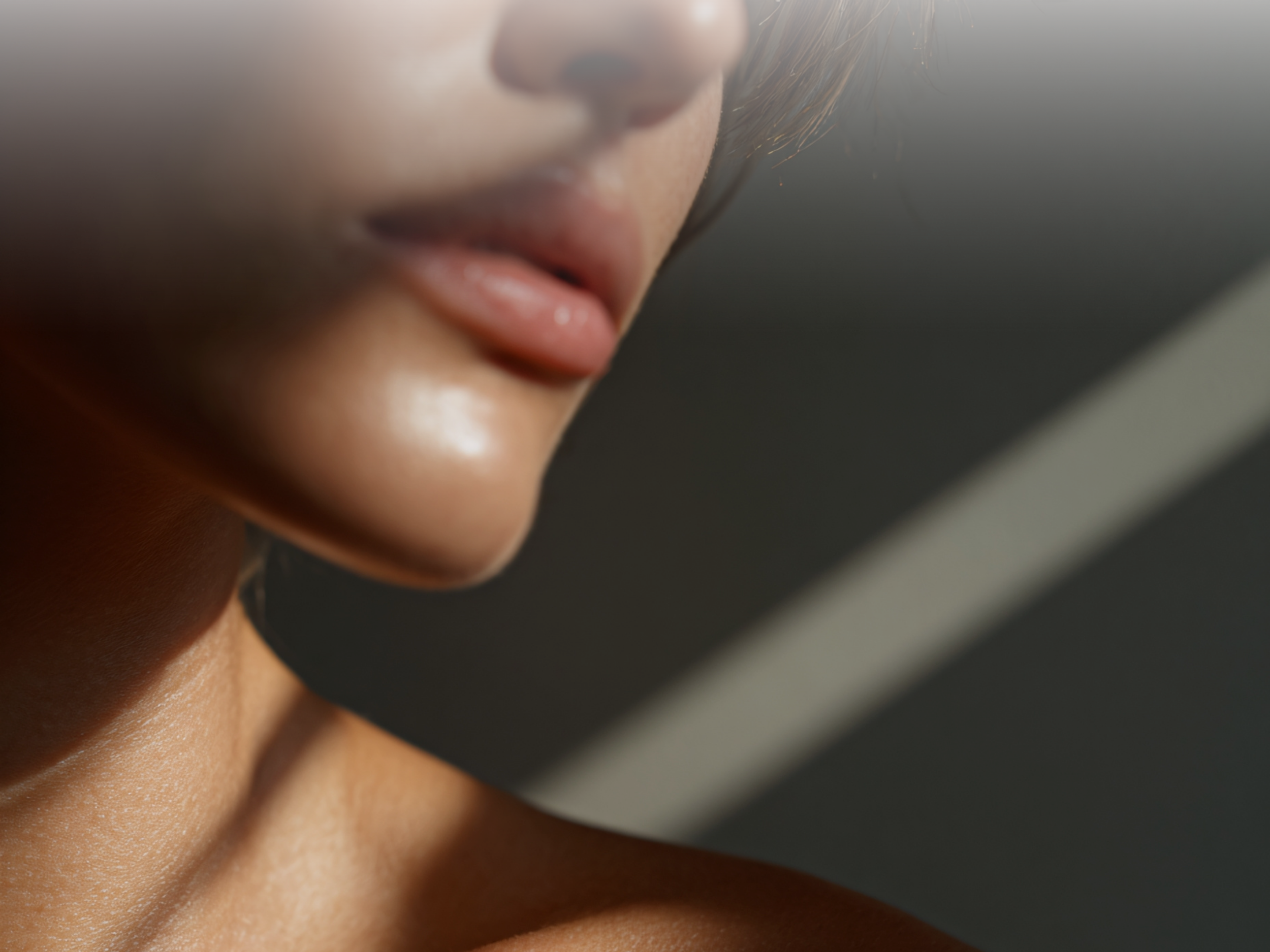 Close-up of a woman's lips and chin with soft lighting, and a blurred background.