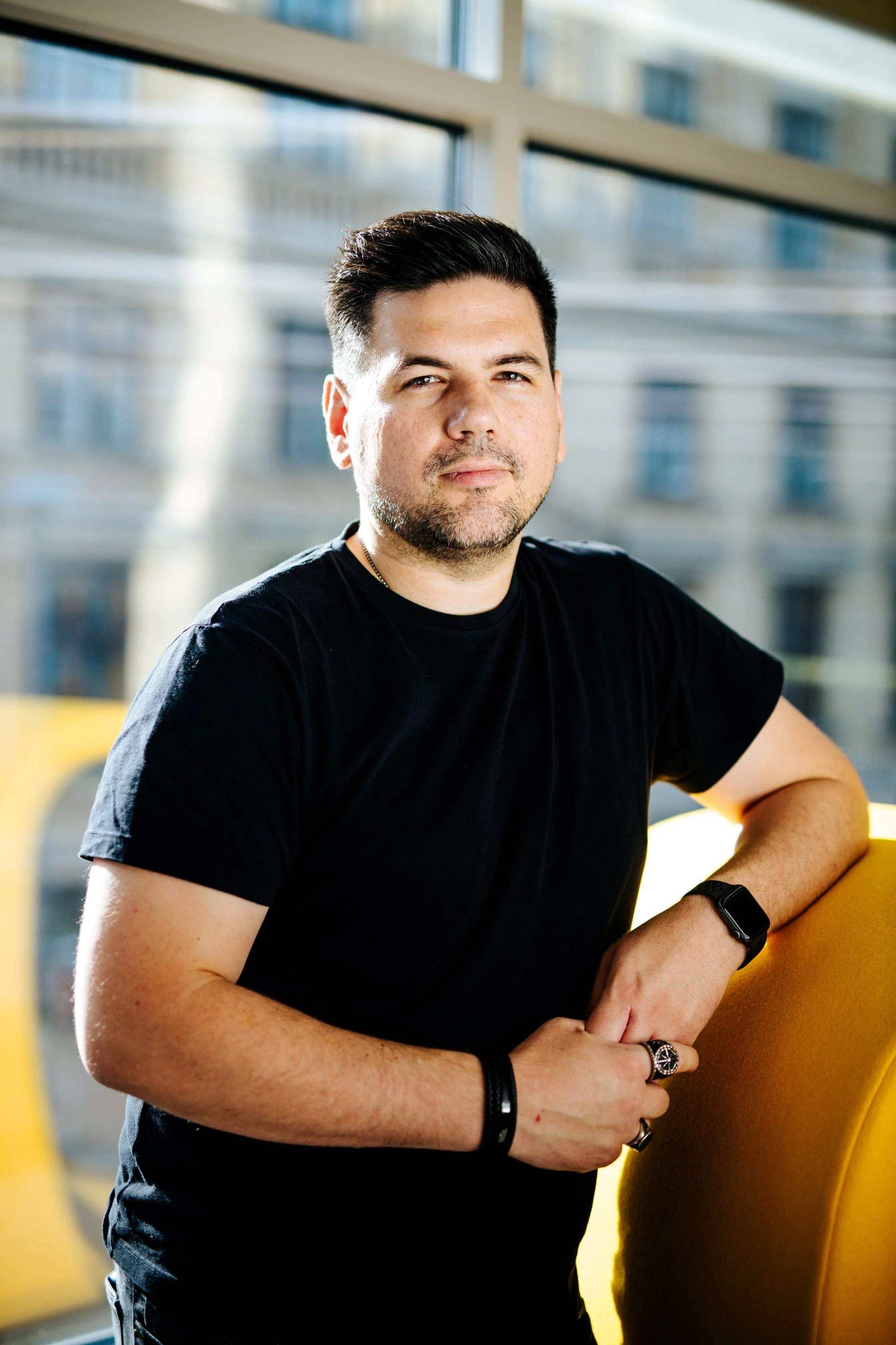 Portrait of a man standing, leaning against a piece of furniture, staring into the camera. This is representing Jerome Athier.
