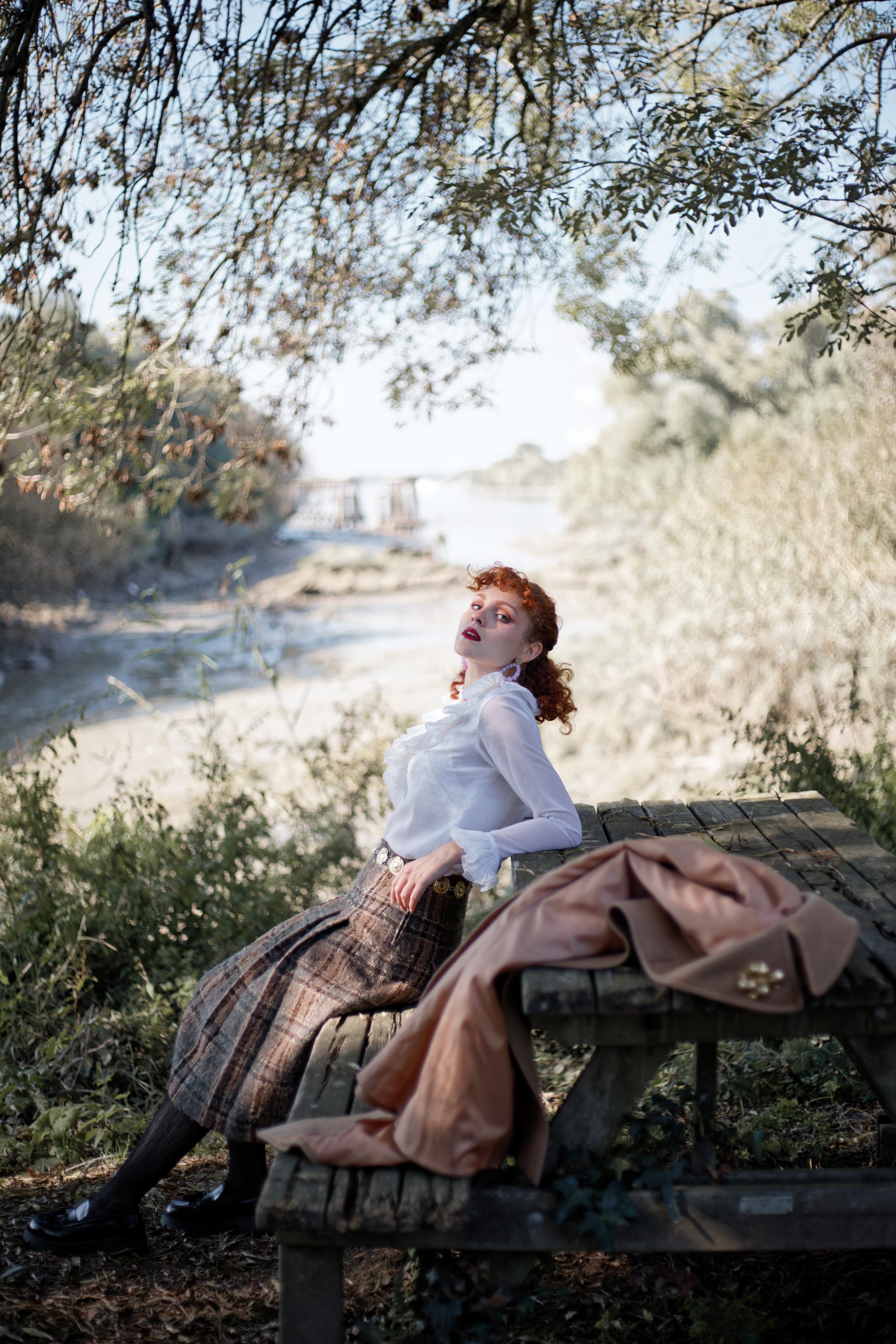 photo portrait d'une jeune femme rousse assise sur un banc devant la loire