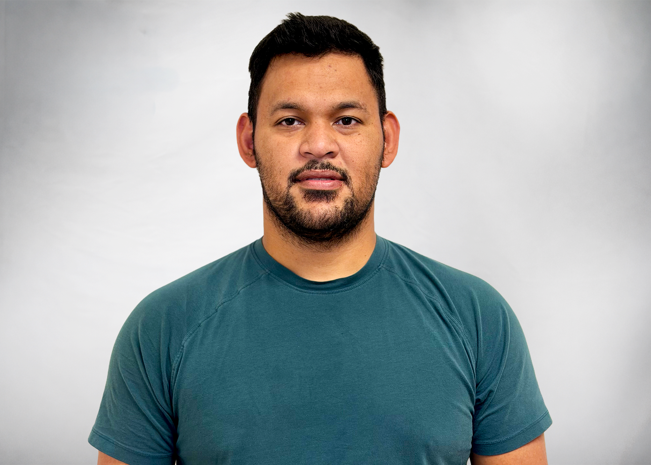 A man in a blue shirt and dark hair staring at the camera