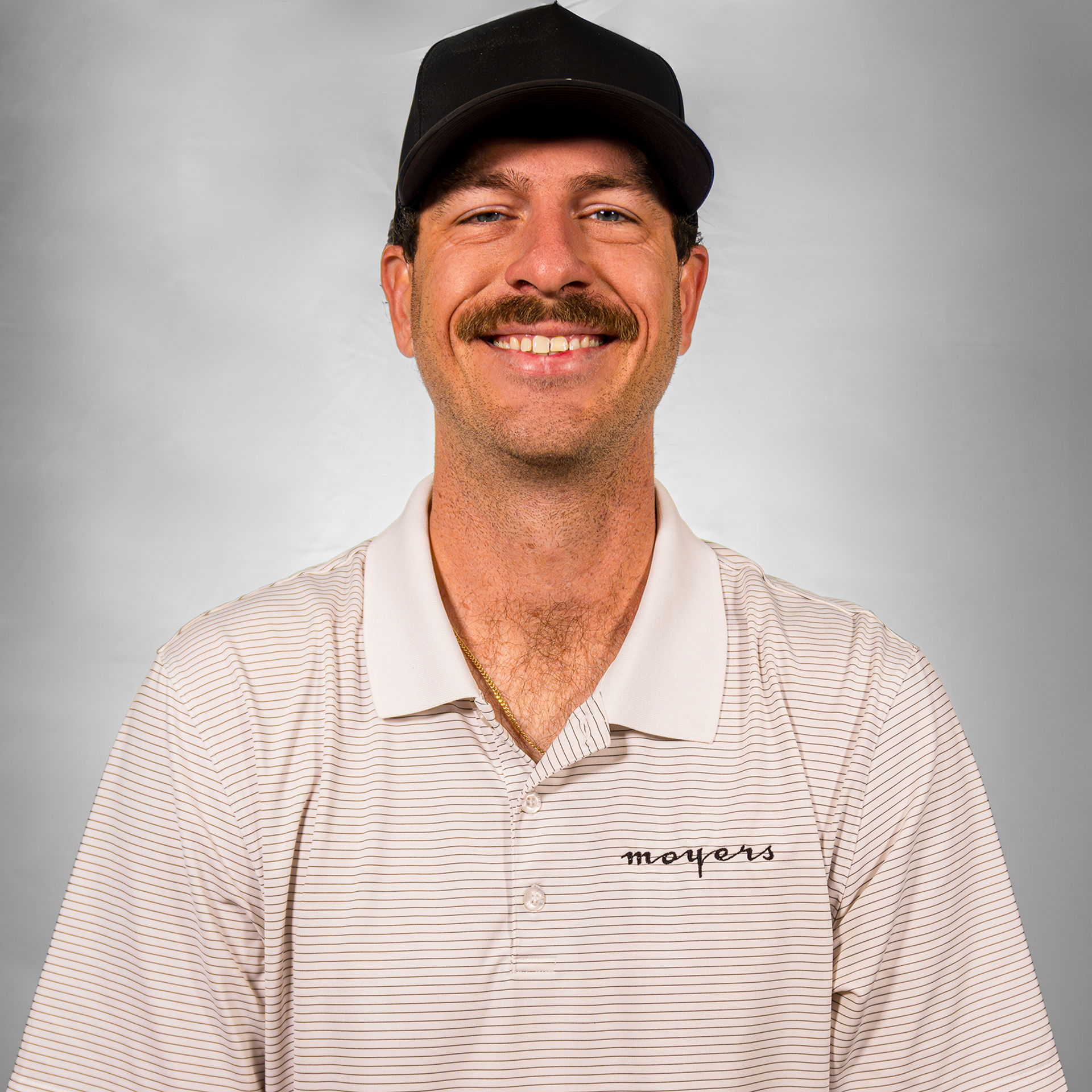 Man wearing a baseball cap and striped polo shirt smiling