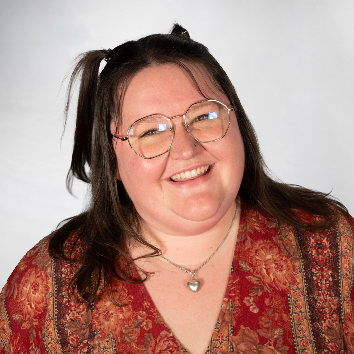 A woman with brown hair and glasses wearing a red dress smiling