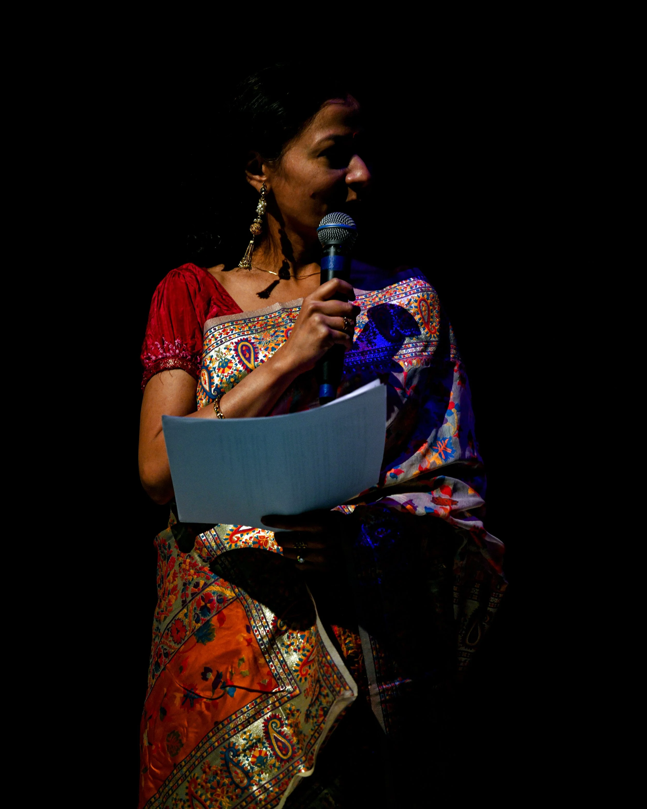 Kaustavi Sarkar on a dark stage with a microphone