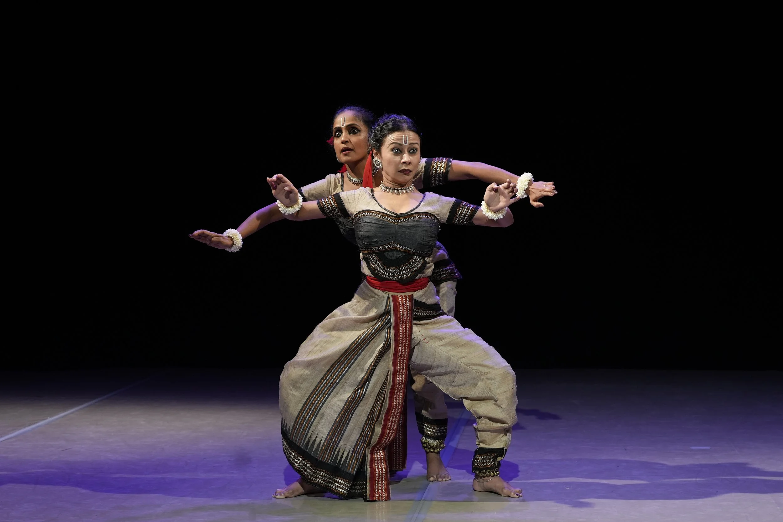 Kaus in a duet with antother dancer on a blackstage, Gajar piece