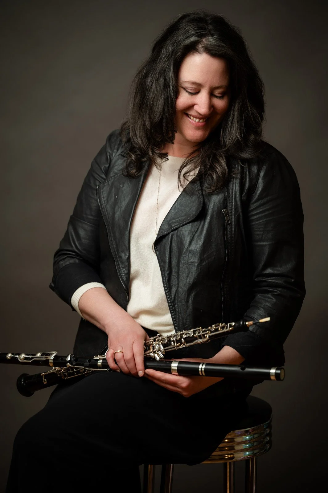 khara wearing a black jaket holding an oboe and wood trad flute