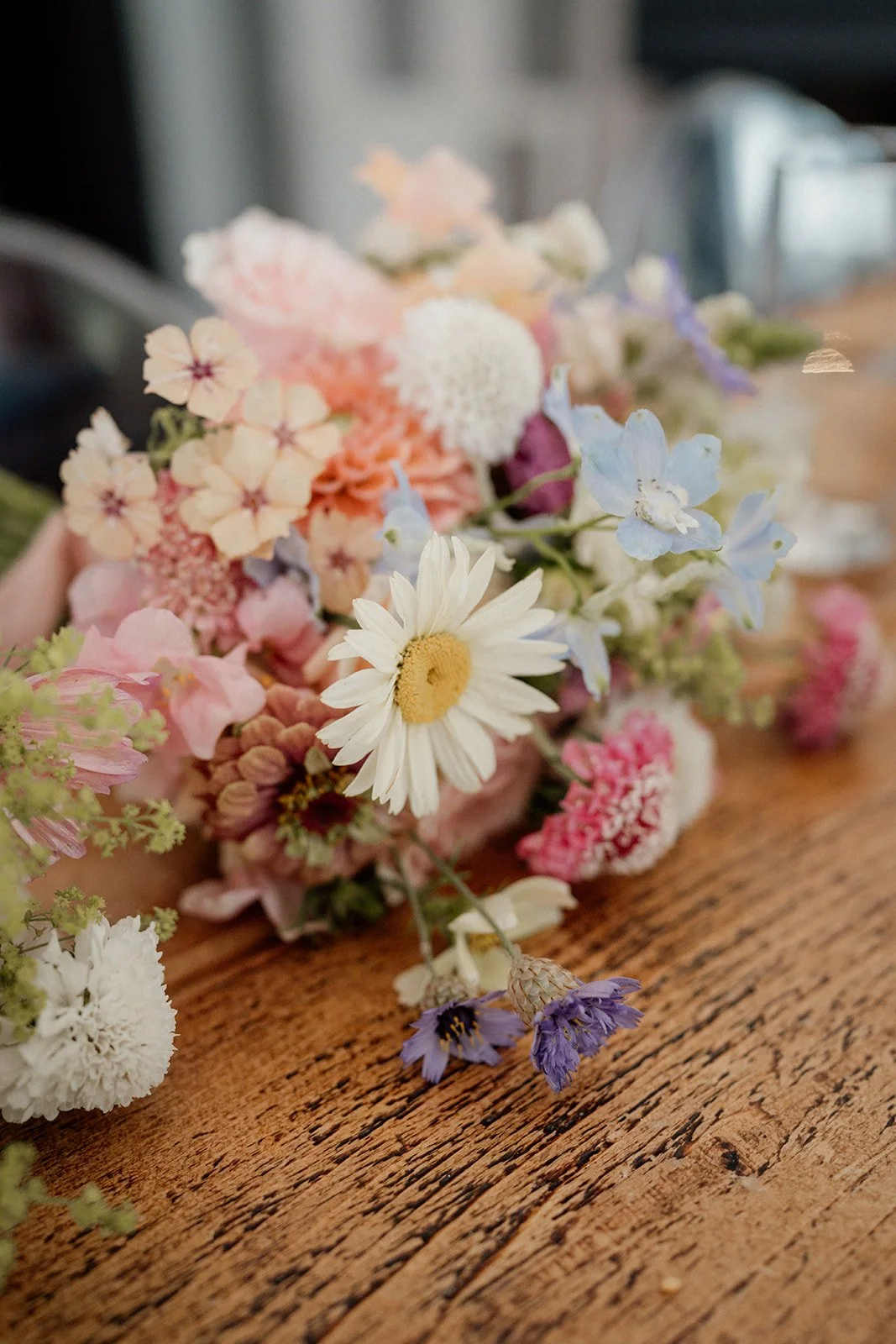 A bouquet of assorted pink, white, purple, and blue flowers resting on a wooden surface.