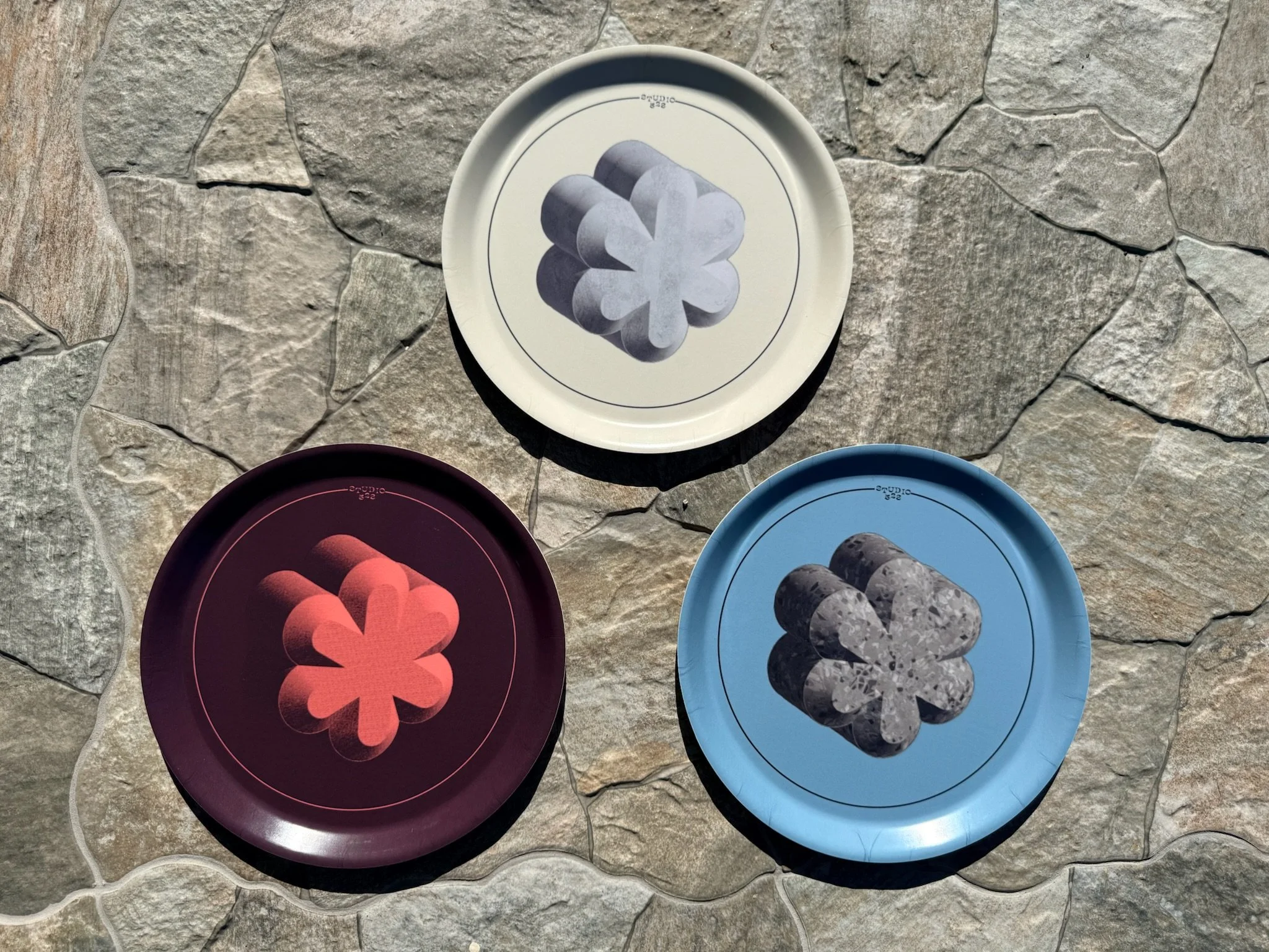 Colorful circular sustainably harvested birch wood trays with abstract designs laid on a stone surface. Made in Sweden.