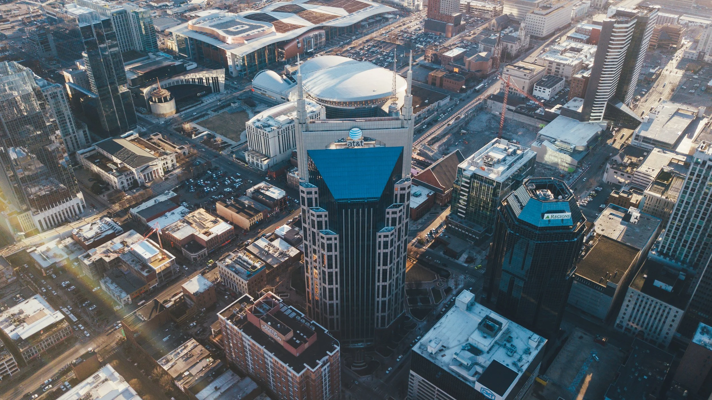 Aerial view of downtown Nashville, Tennessee, featuring the AT&T Building, known as the 'Batman Building,' with its twin spires and distinctive architecture, surrounded by modern skyscrapers and city streets.