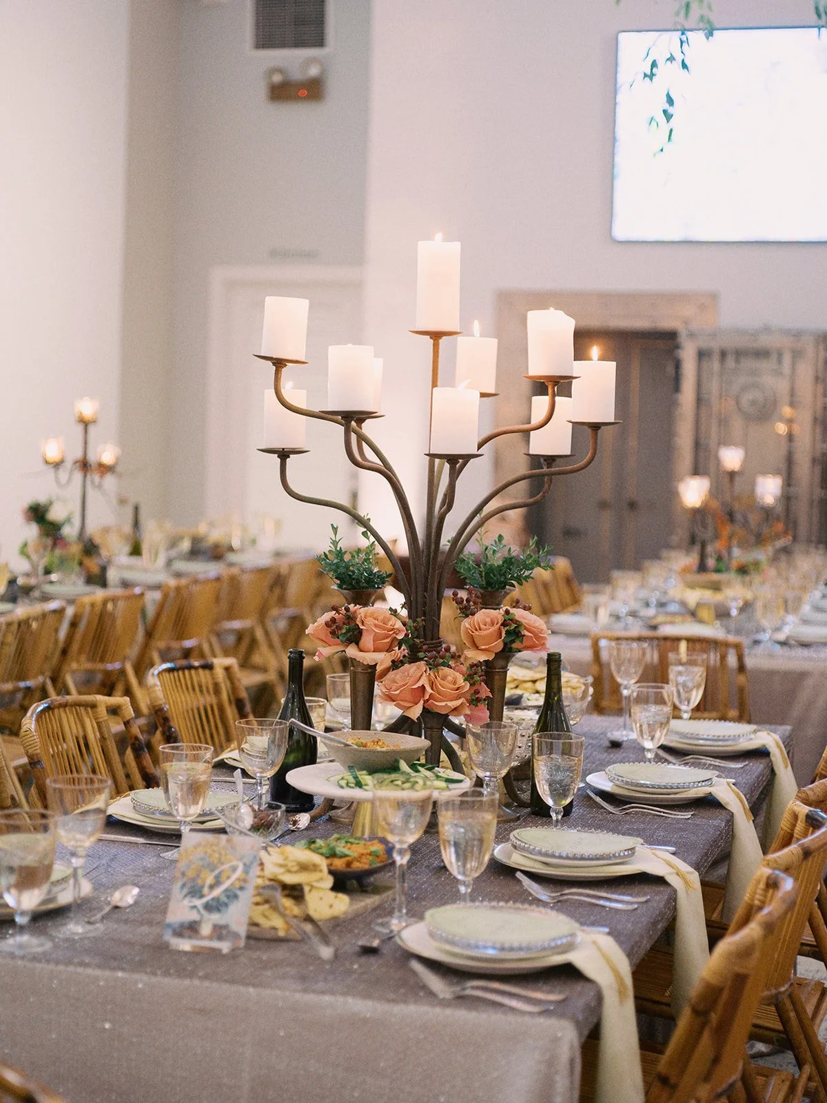 Decorated banquet table with a large antique candelabra centerpiece with candles and flowers, set for a formal event.