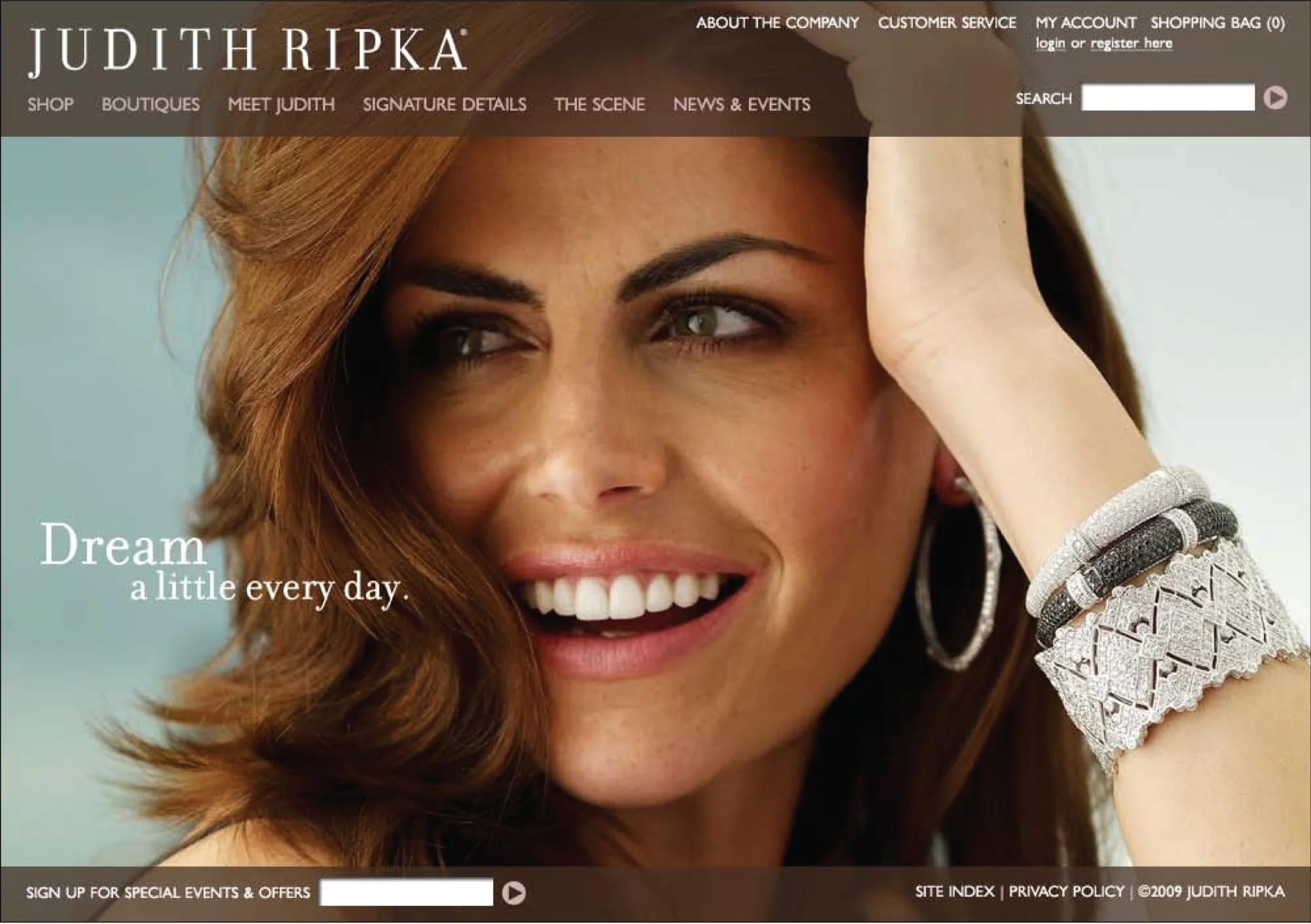 Close-up of a smiling woman with reddish-brown hair, wearing jewelry, in a website header for Judith Ripka with navigation menu and search bar.