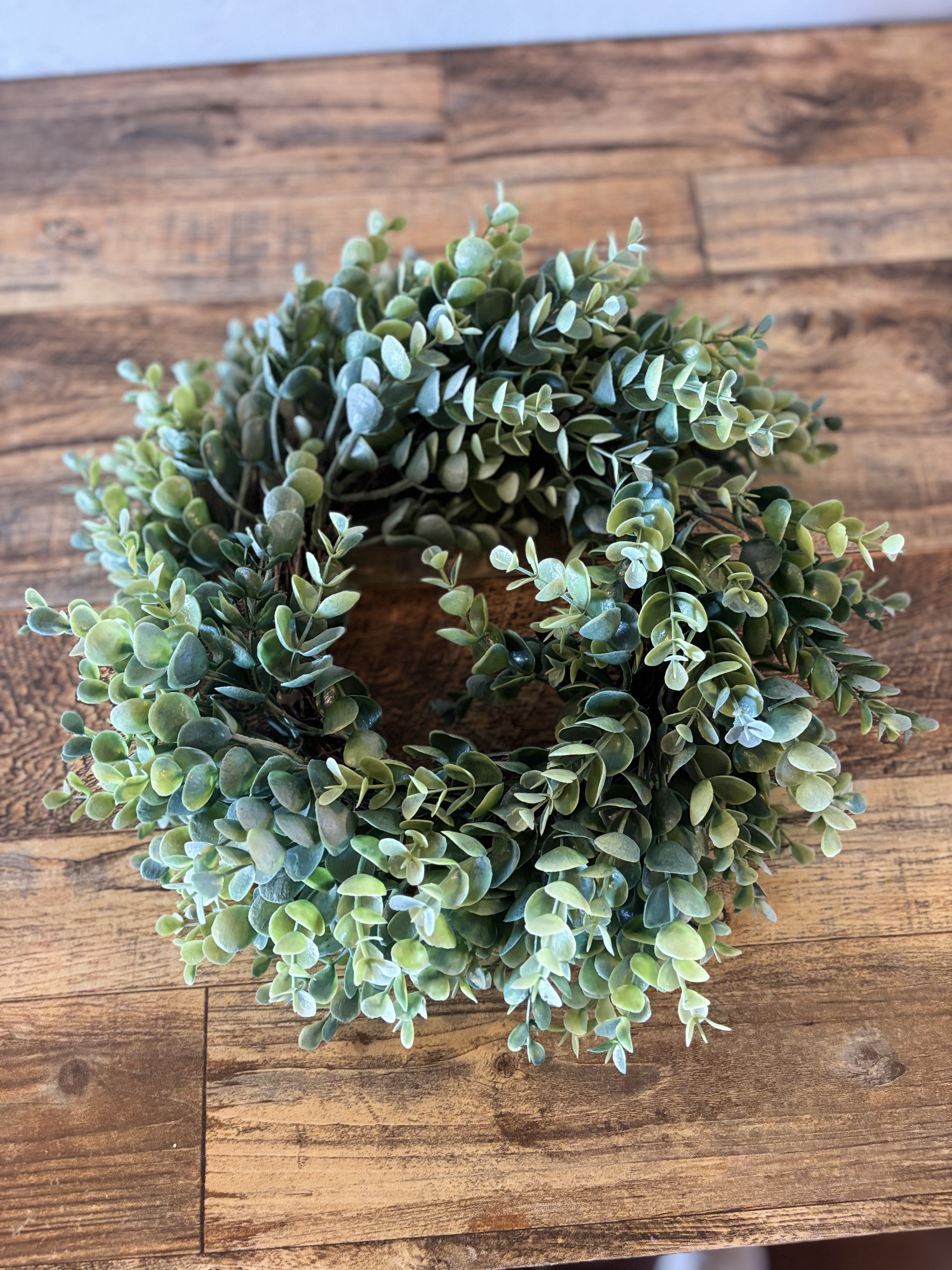 Green artificial wreath on wooden surface.