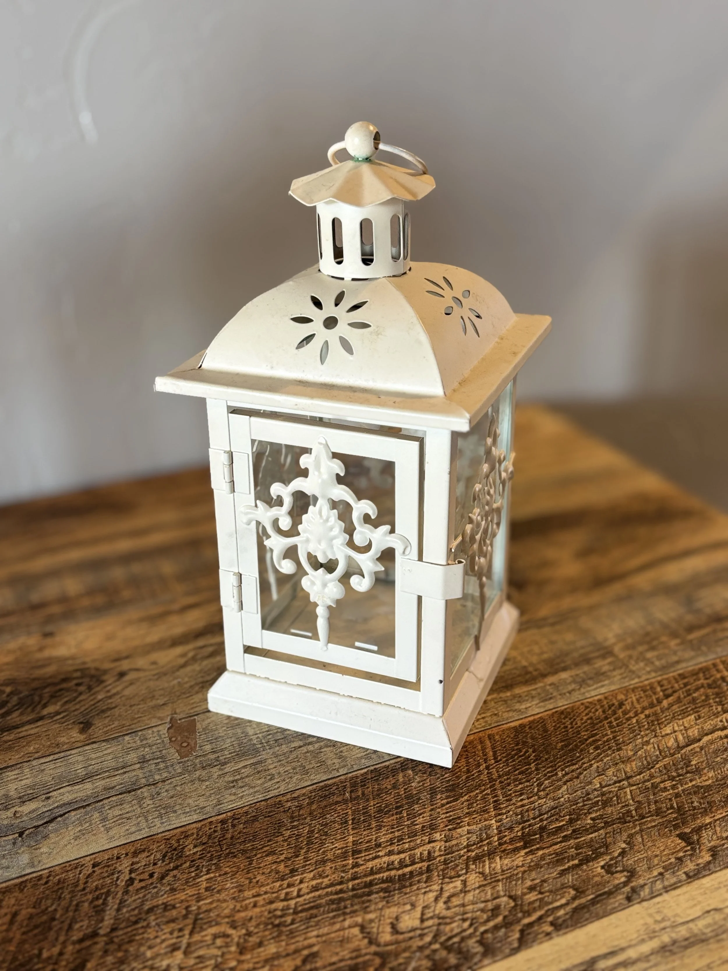 White decorative lantern with intricate patterns on a wooden surface.