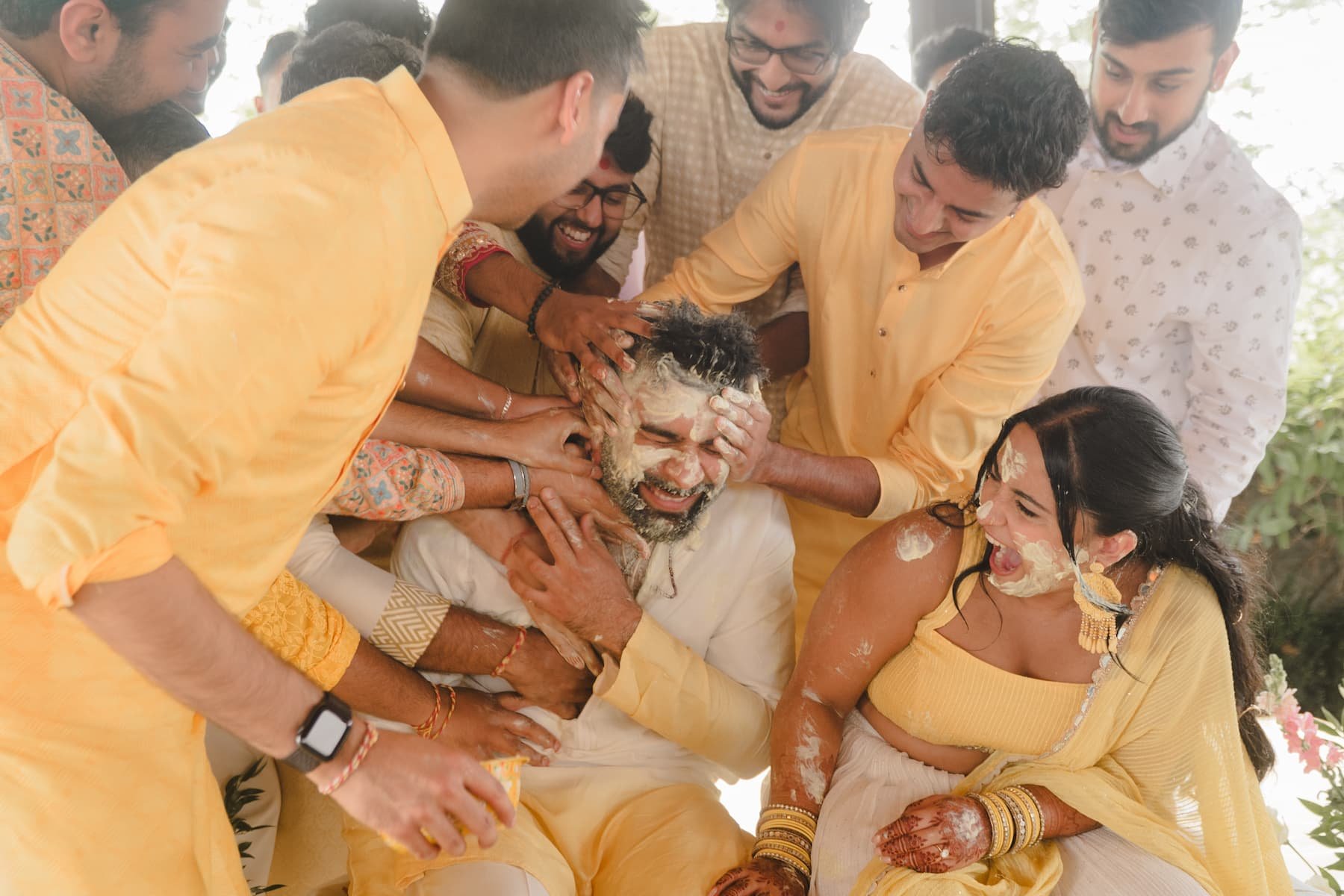 Friends and family playfully cover groom Sagar in Haldi paste during Ashika and Sagar's Haldi ceremony at Arlington Estate before their South Asian wedding.