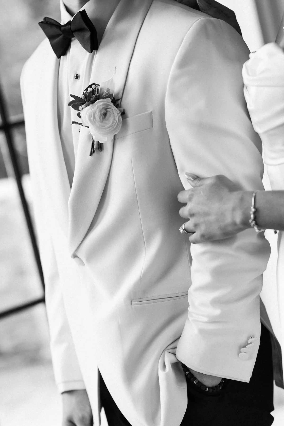 Close-up of the groom's white tuxedo jacket and floral boutonniere during a wedding at Harding Waterfront Estate.