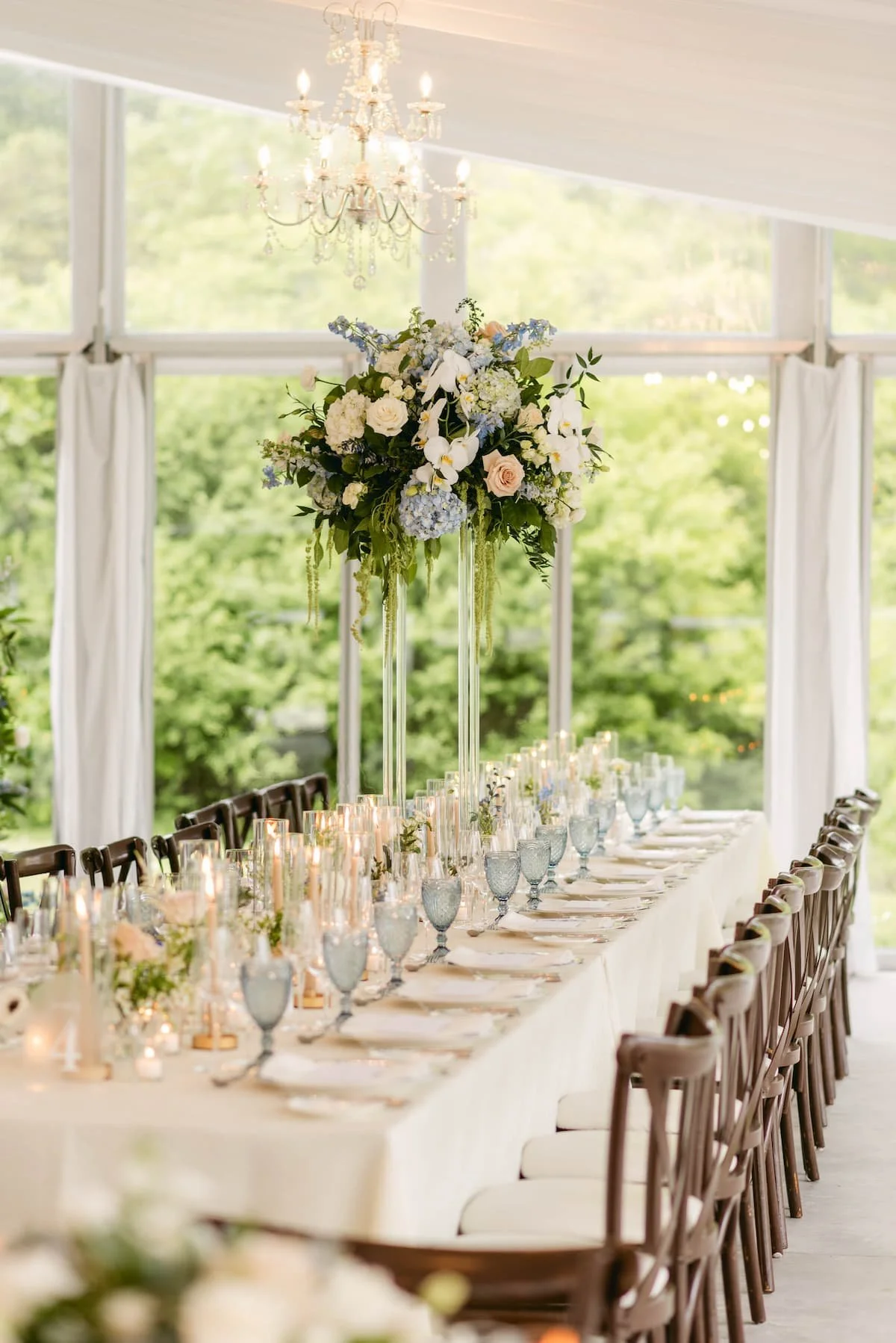 Tall floral centrepiece with blue and white blooms displayed on a long reception table at Harding Waterfront Estate.