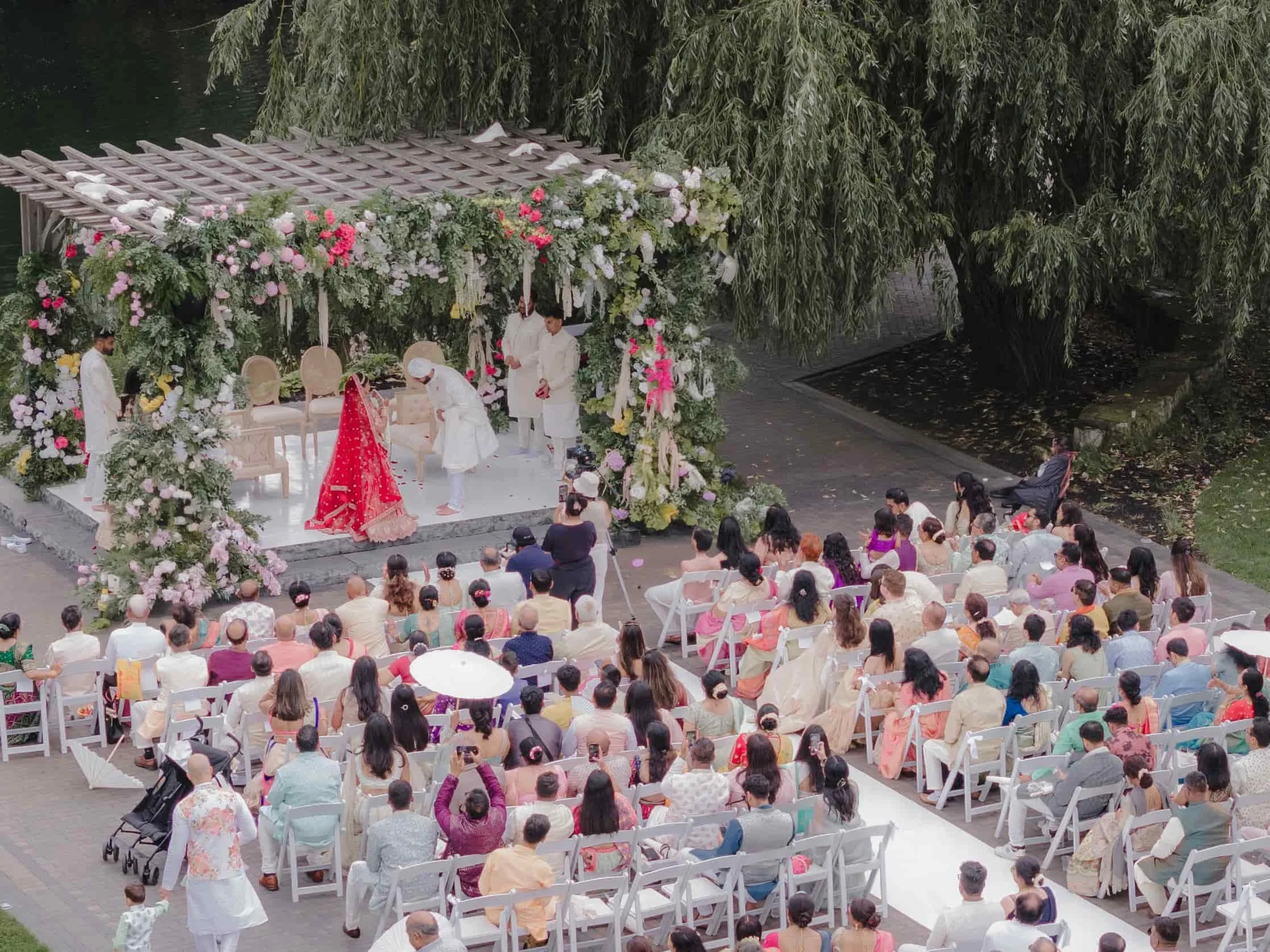 Aerial shot of Ashika and Sagar during the varmala exchange beneath a floral mandap at their outdoor Hindu wedding at Arlington Estate.