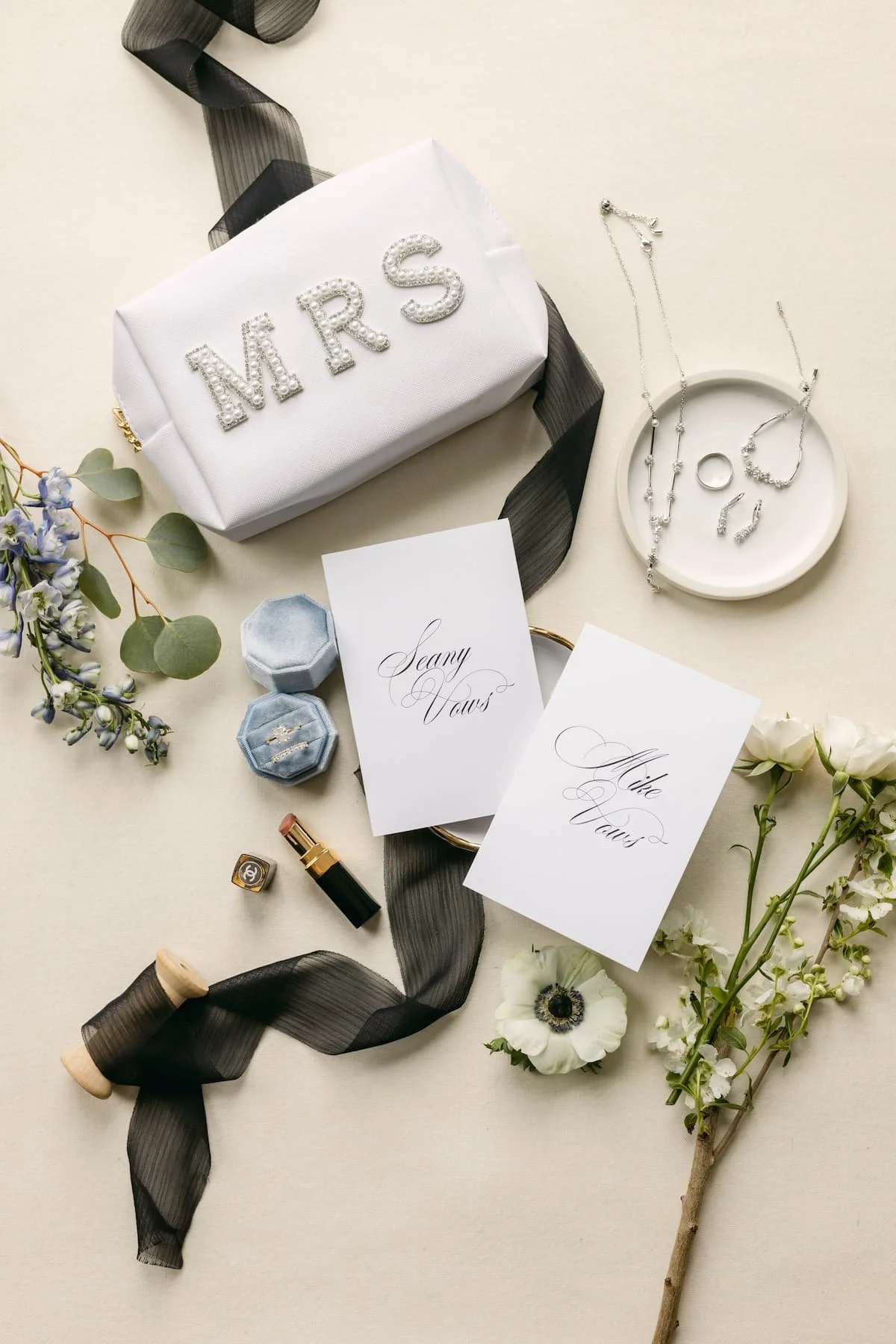 Bridal details including vow books, jewellery, wedding rings, florals and a personalized bridal bag styled for a wedding at Harding Waterfront Estate.