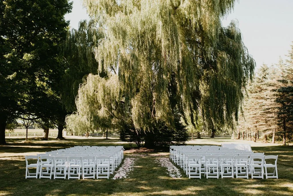 Luxury outdoor wedding ceremony with abundant white florals, elegant seating and a timeless ceremony backdrop designed for an elevated guest experience.