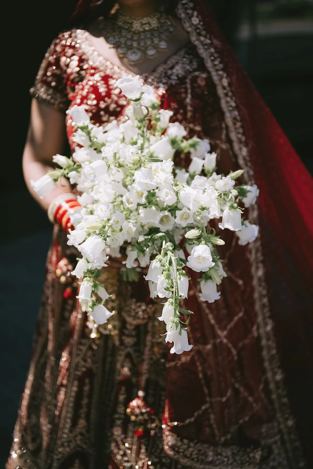 Bride holding a cascading bouquet of white campanula flowers before a modern Hindu wedding ceremony in Toronto.