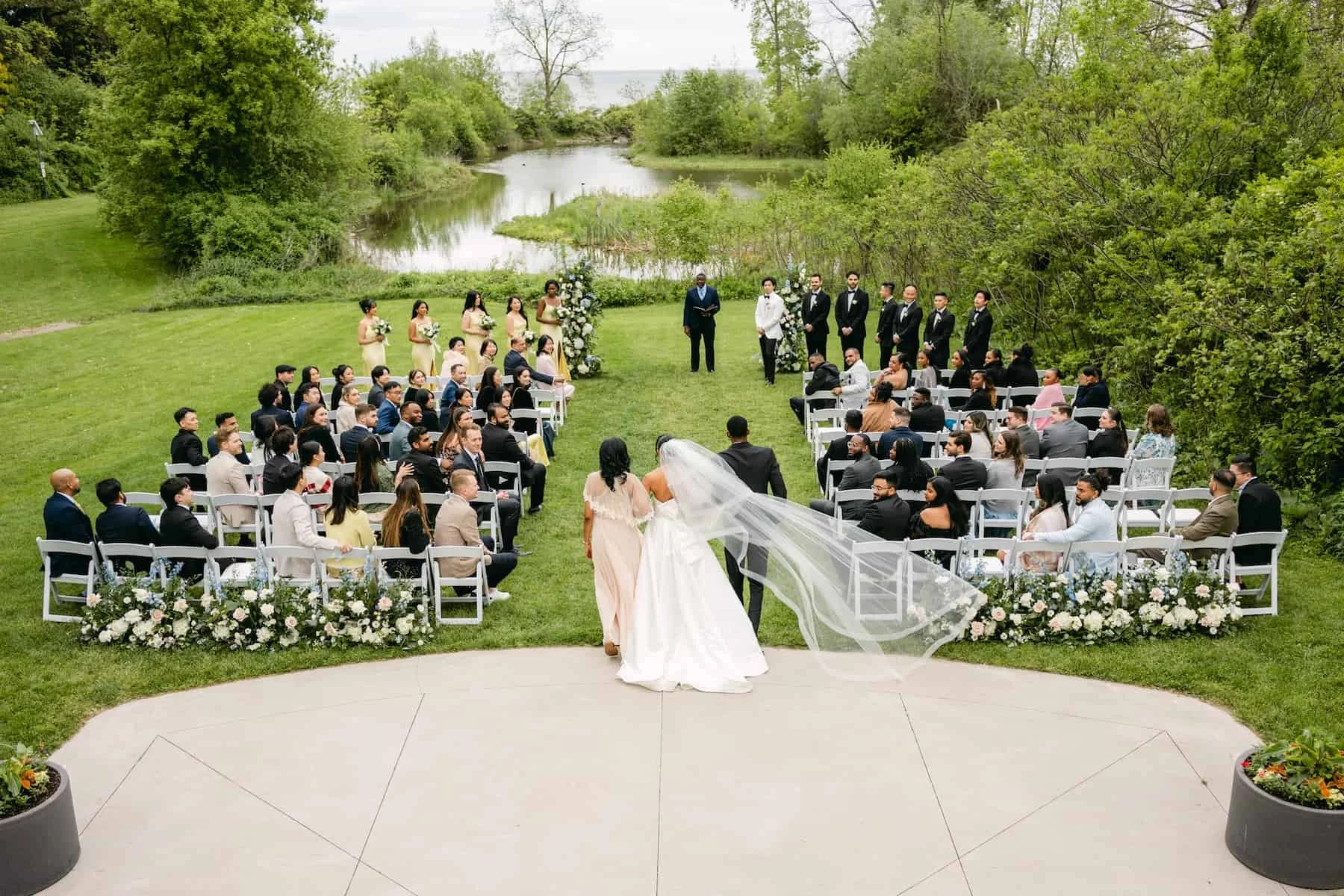 Guests gather for an outdoor wedding ceremony overlooking the waterfront at Harding Waterfront Estate in Mississauga, Ontario.