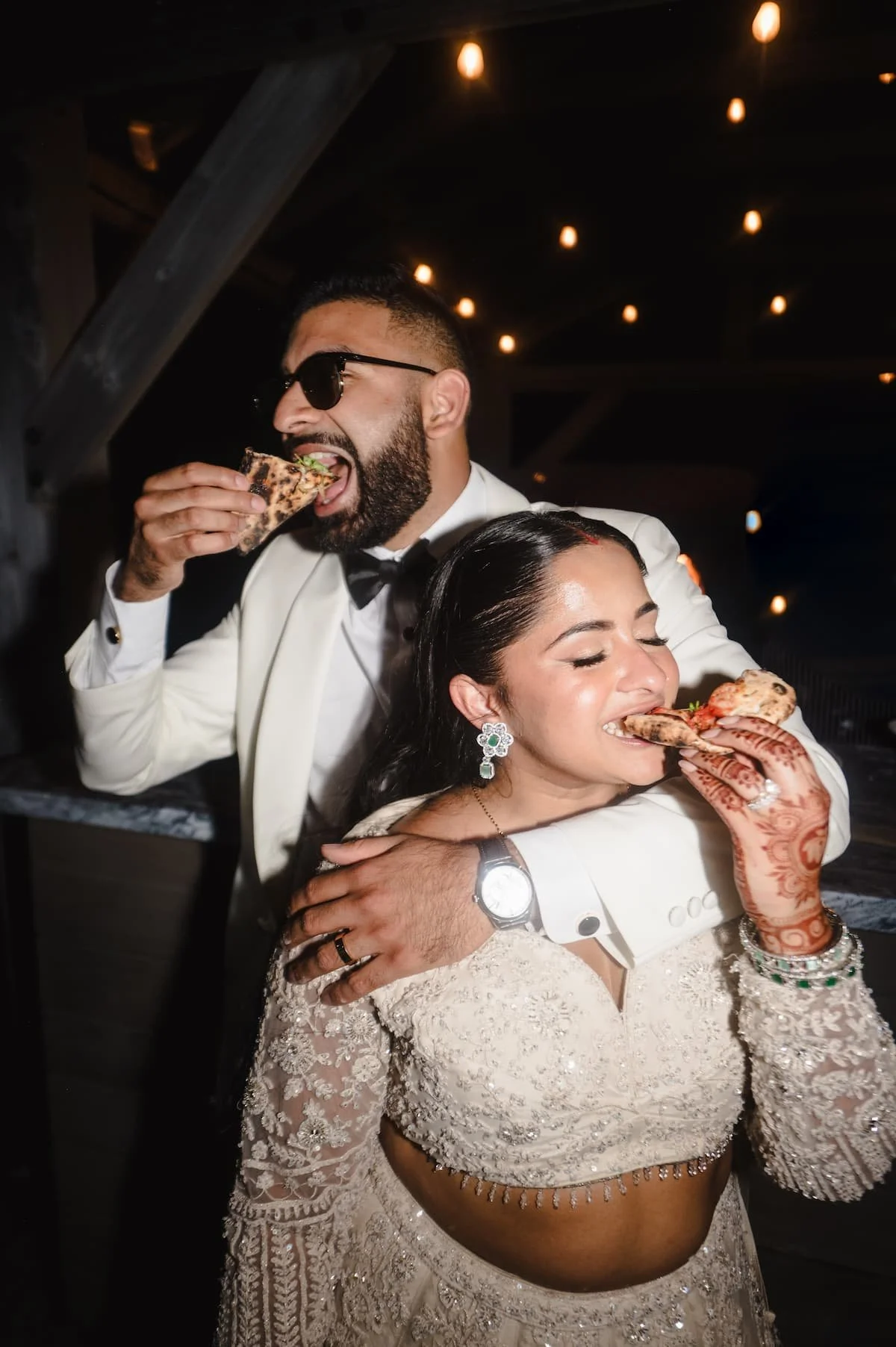 Bride and groom enjoying late-night pizza during their luxury South Asian wedding reception at Arlington Estate.