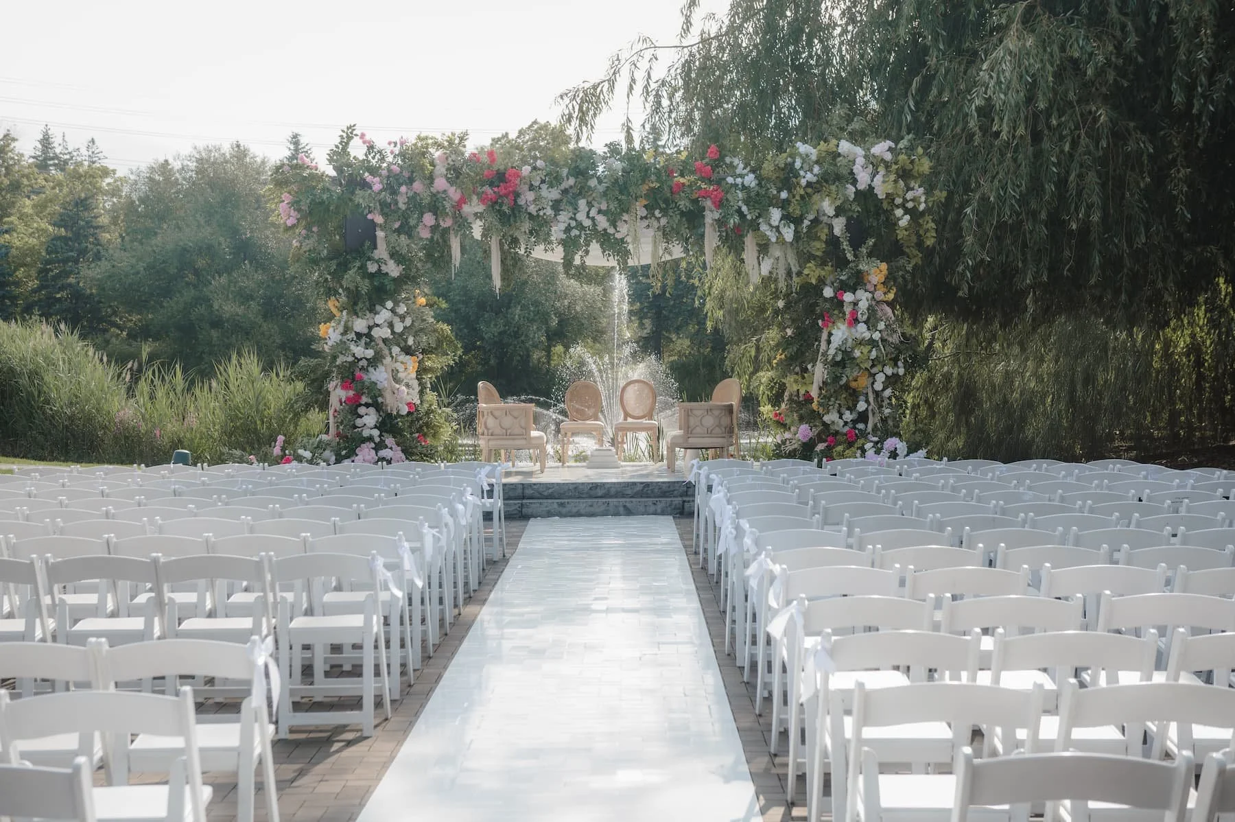 Ashika and Sagar's outdoor Hindu wedding ceremony at Arlington Estate featuring a lush floral mandap and white aisle overlooking the water.