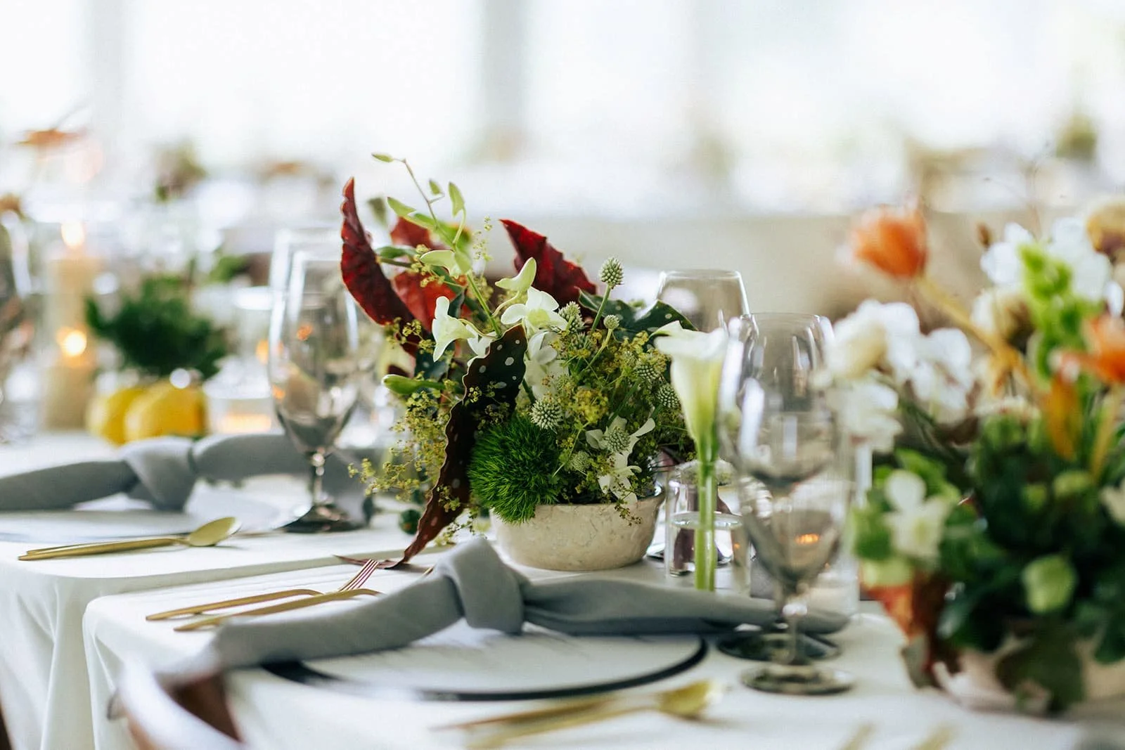 Close-up of luxury wedding table décor featuring taper candles, fruit and floral arrangements.