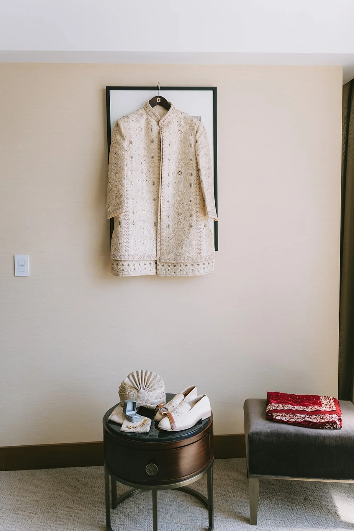Ivory embroidered sherwani with traditional accessories displayed before a modern Hindu wedding ceremony in Toronto, including embroidered shoes, turban, watch, and wedding rings.