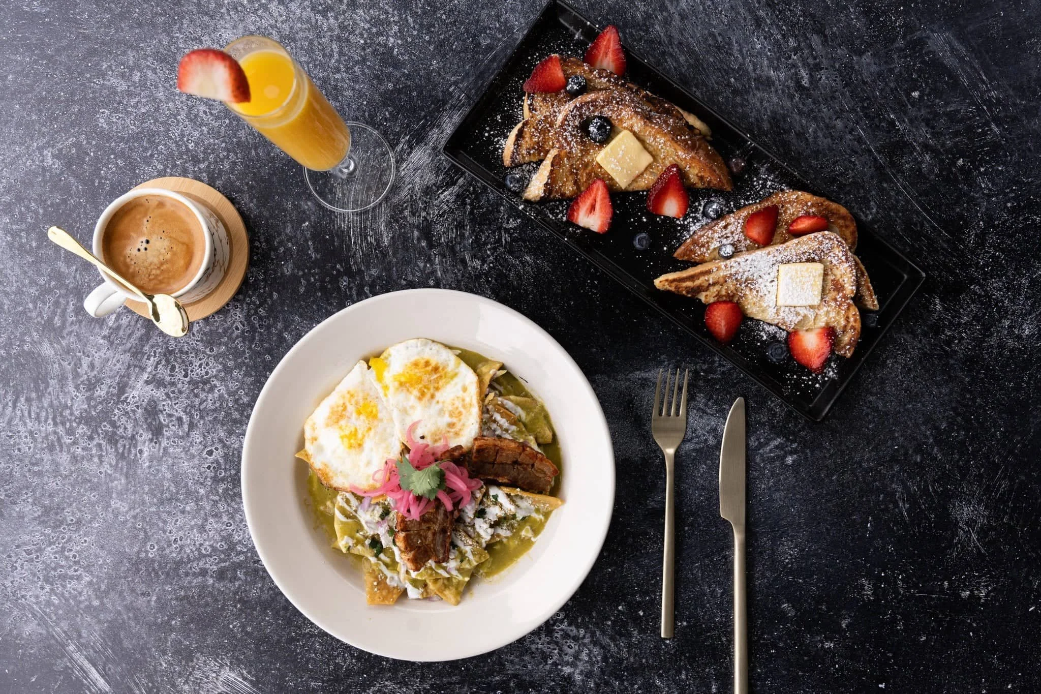 The image shows a table set with plates of food and a glass of liquid. The tableware includes forks, coffee cups, and plates. This dish is s