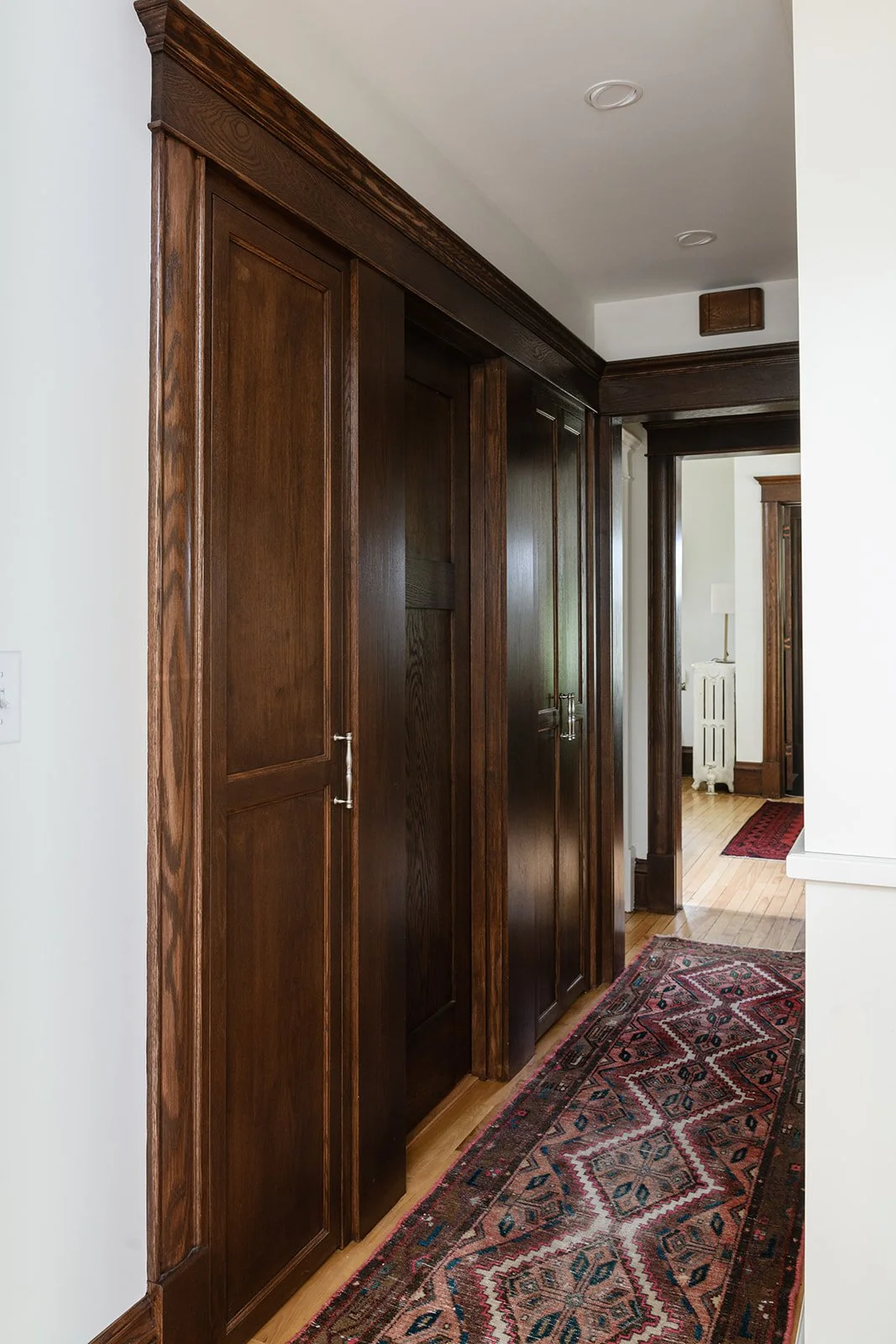 This hallway view showcases the newly installed dark-stain, salvaged, oak door and custom-matched trim