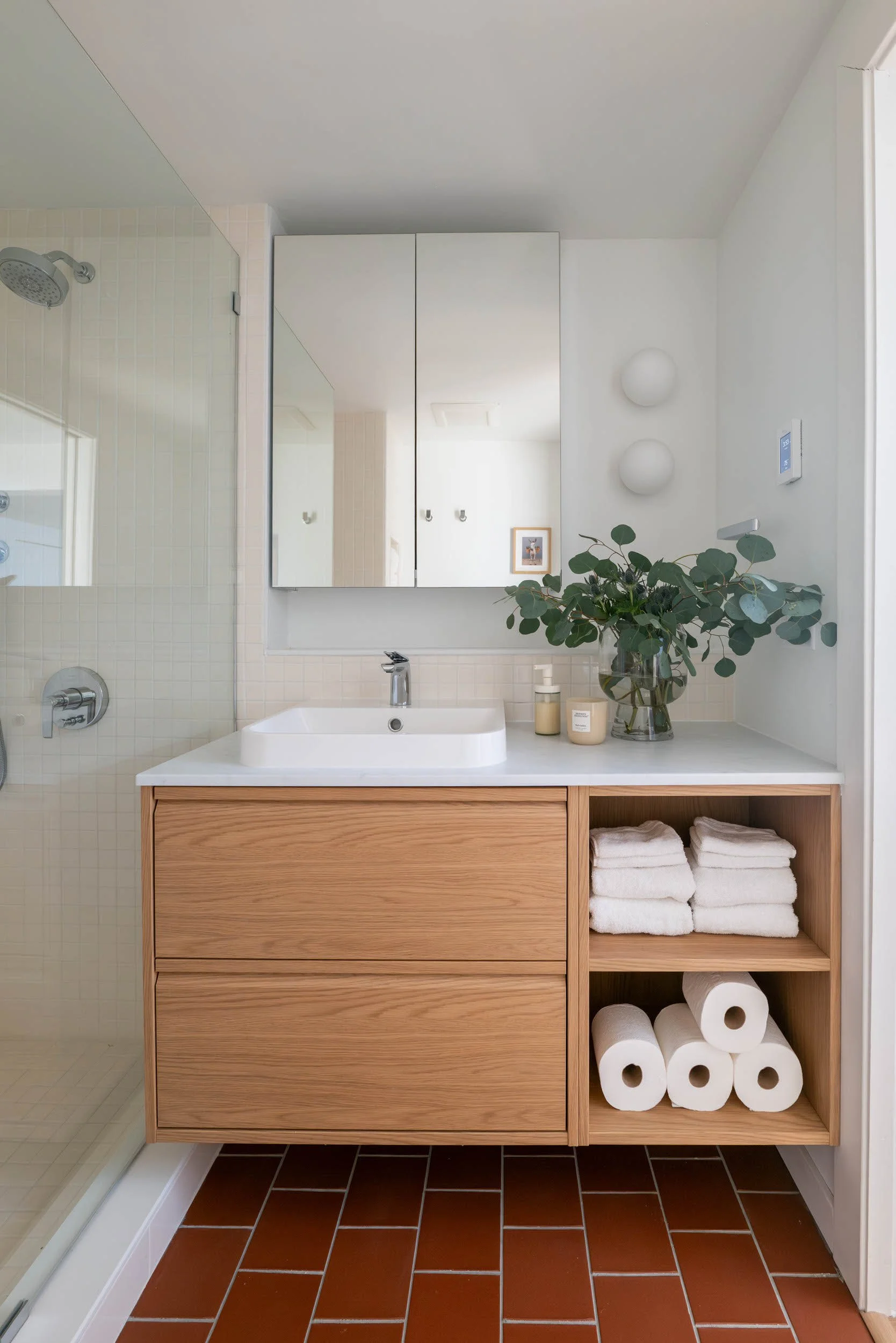 Mid-century modern bathroom with white oak floating vanity, mirror medicine cabinet and terracota tile floors