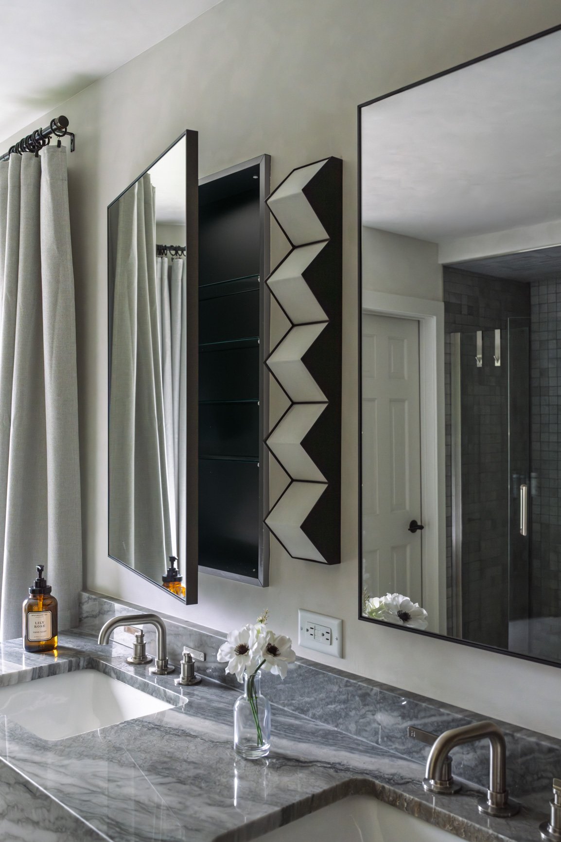 Luxurious bathroom featuring a stunning quartz countertop with prominent blue grey veining, integrated sink, and modern brushed nickel faucet. The sleek design is complemented by a dark wood vanity, a wall-mounted medicine cabinet, and a simple glass