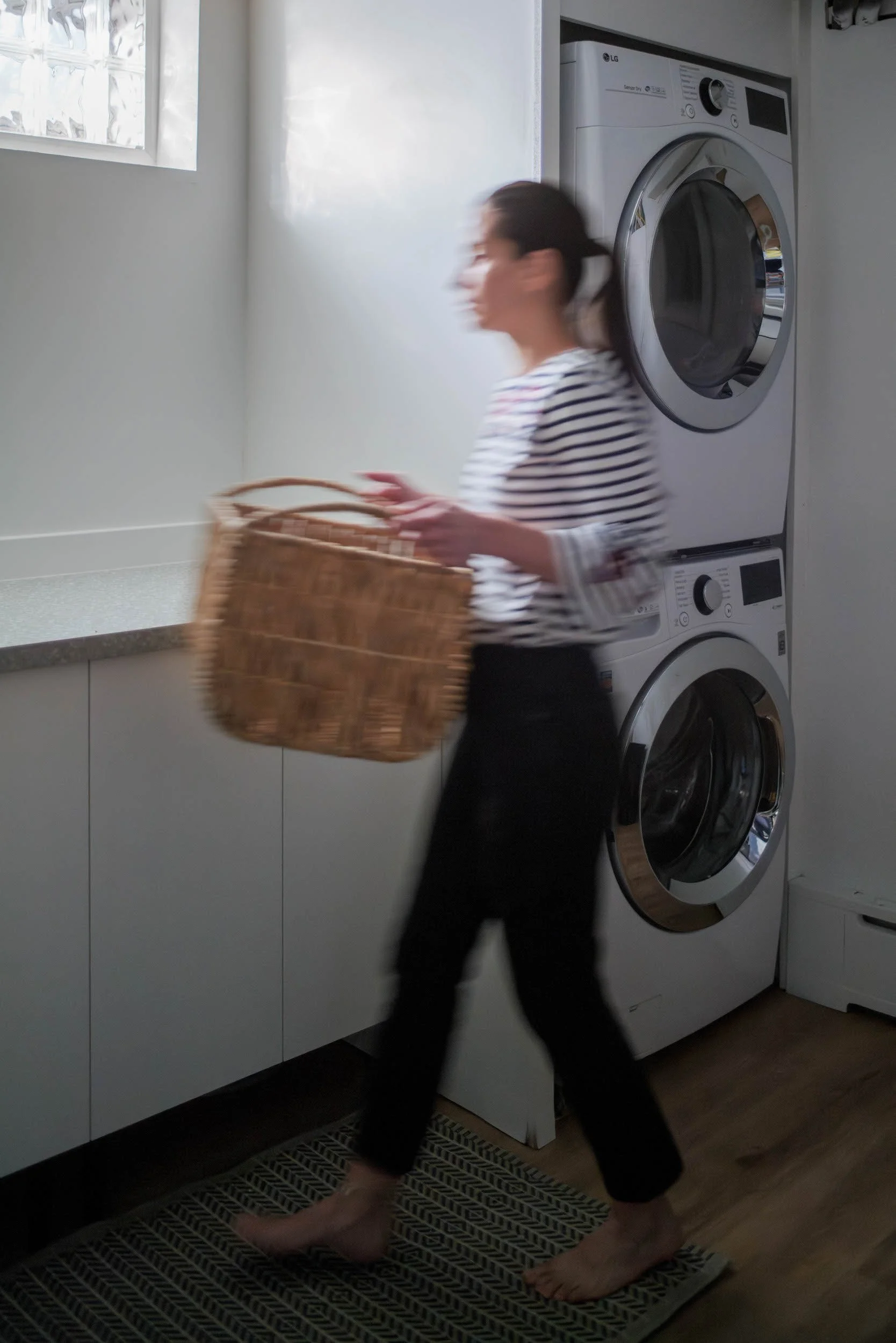 Woman doing laundry in modern white laundry with stackable washer and dryer