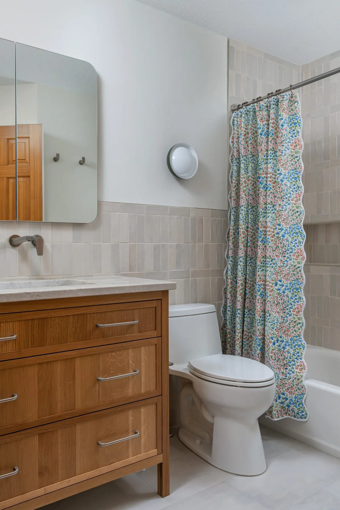 This image captures a bright and serene bathroom with a focus on natural textures and modern, clean lines. A light-colored white oak vanity, features a pristine, light-colored stone countertop and a sleek, wall-mounted faucet.
Above the vanity, a ro