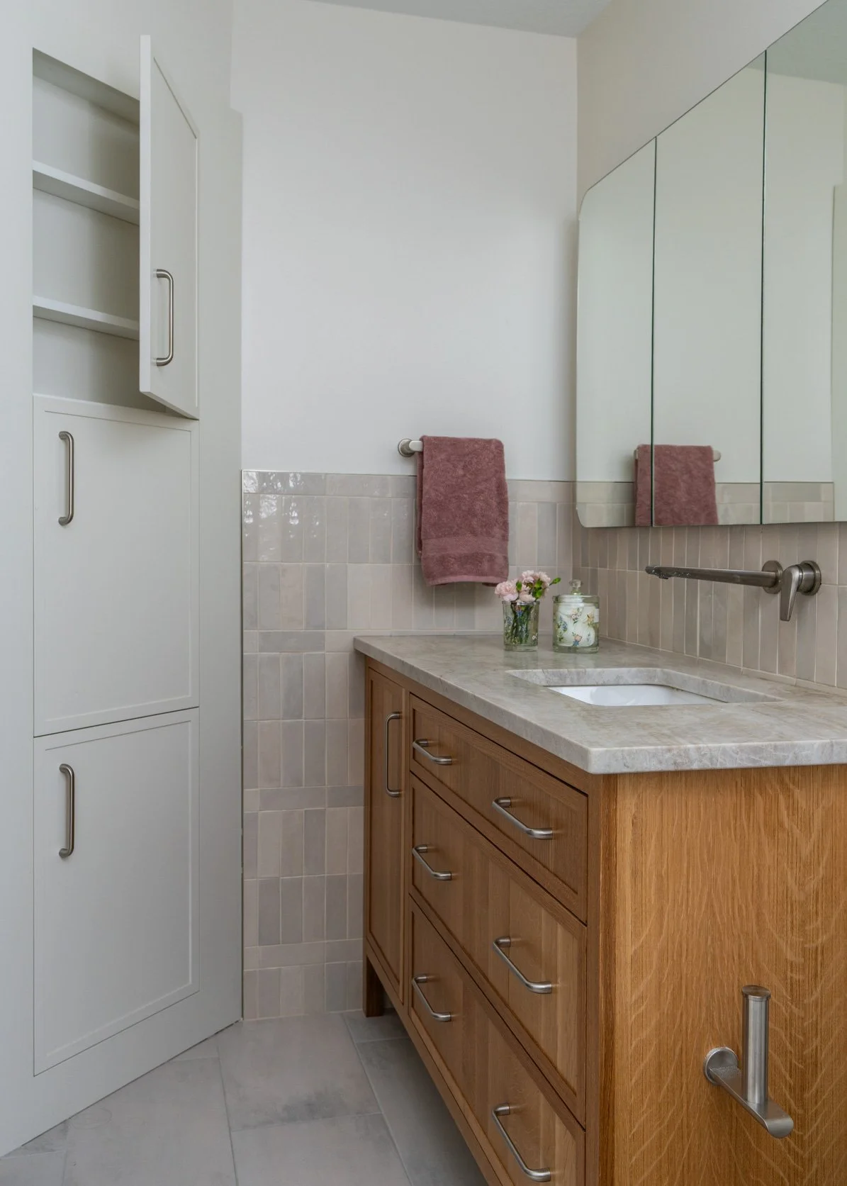 This image features a wonderful triple storage between studs. To the right a white oak vanity with a wall mounted faucet and a triple medicine cabinet above