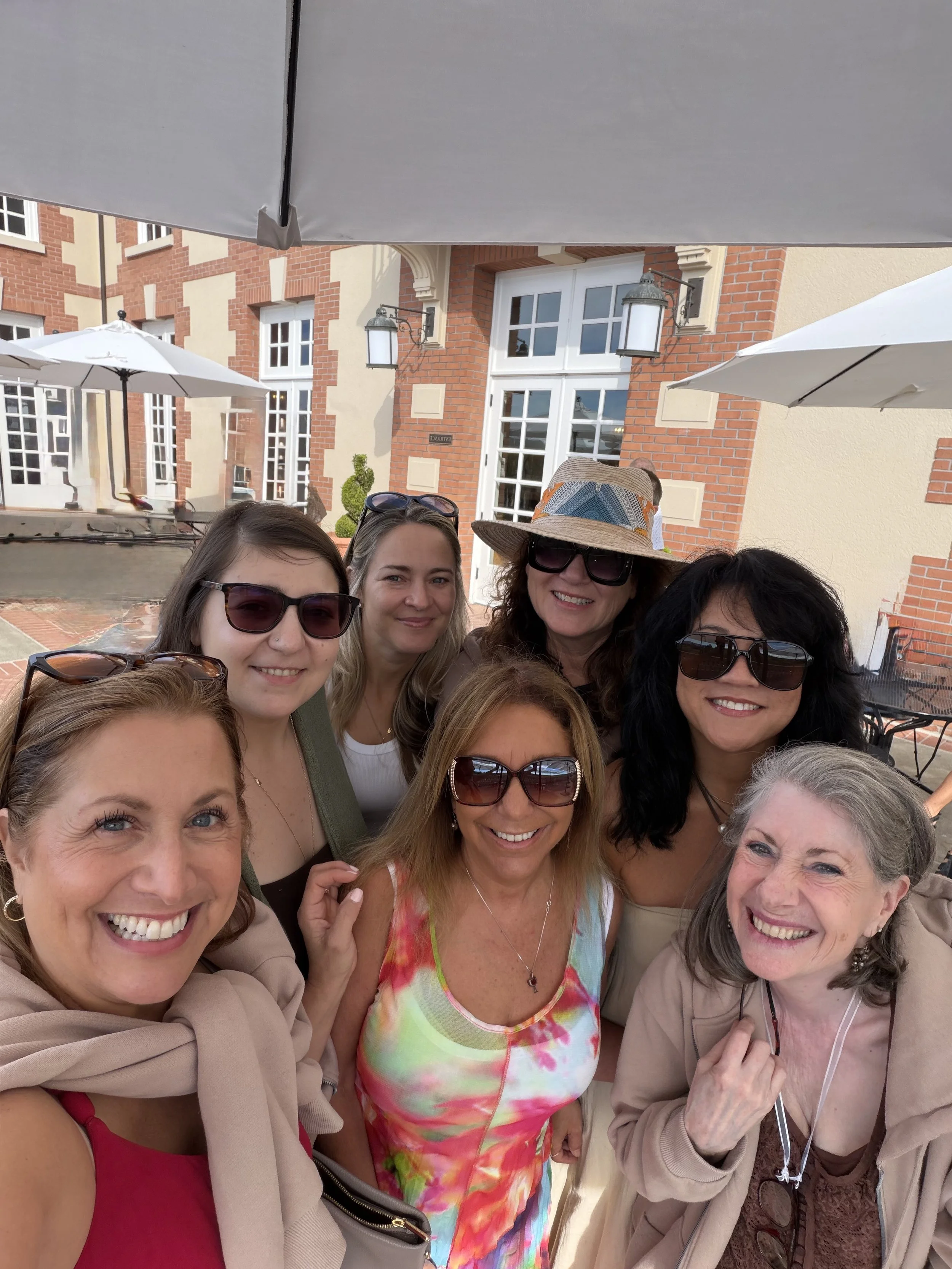 Seven women from Sisters of the Vine posing together outside Domaine Carneros in Napa Valley at the start of their wine country trip.