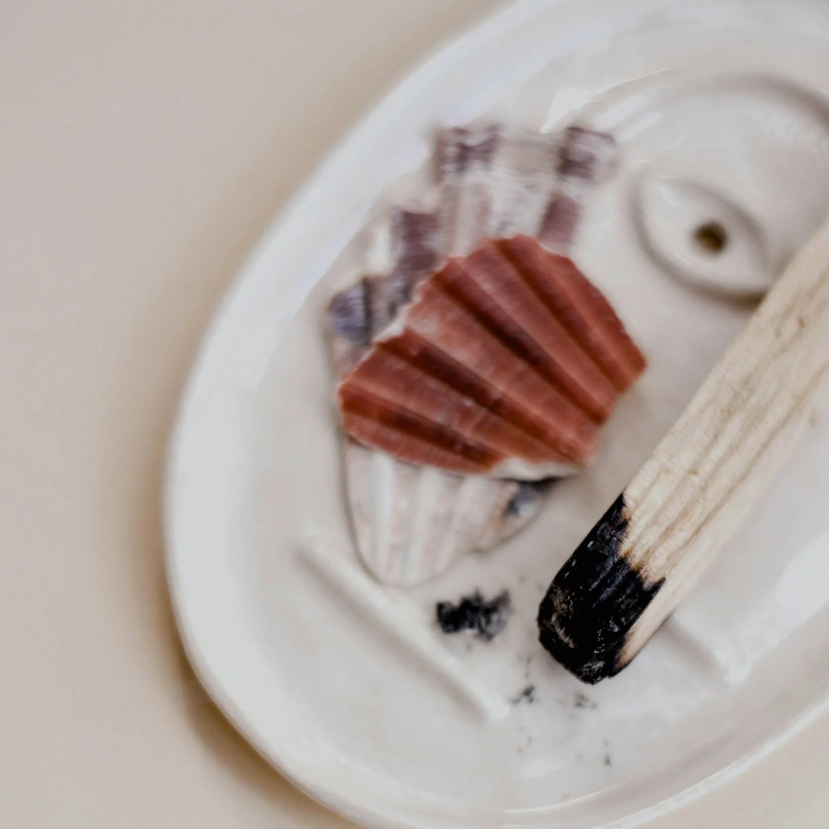 Shell-shaped soaps in pink, purple, and cream colors on a white dish with a wooden handle