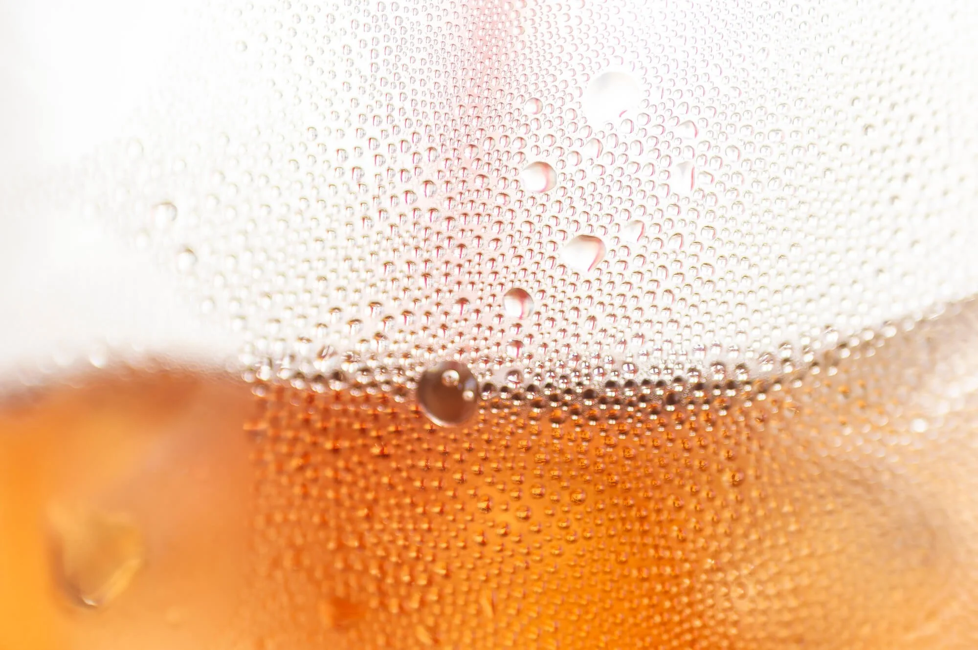 Close-up photograph of a carbonated beverage with bubbles on the inside of a transparent glass.