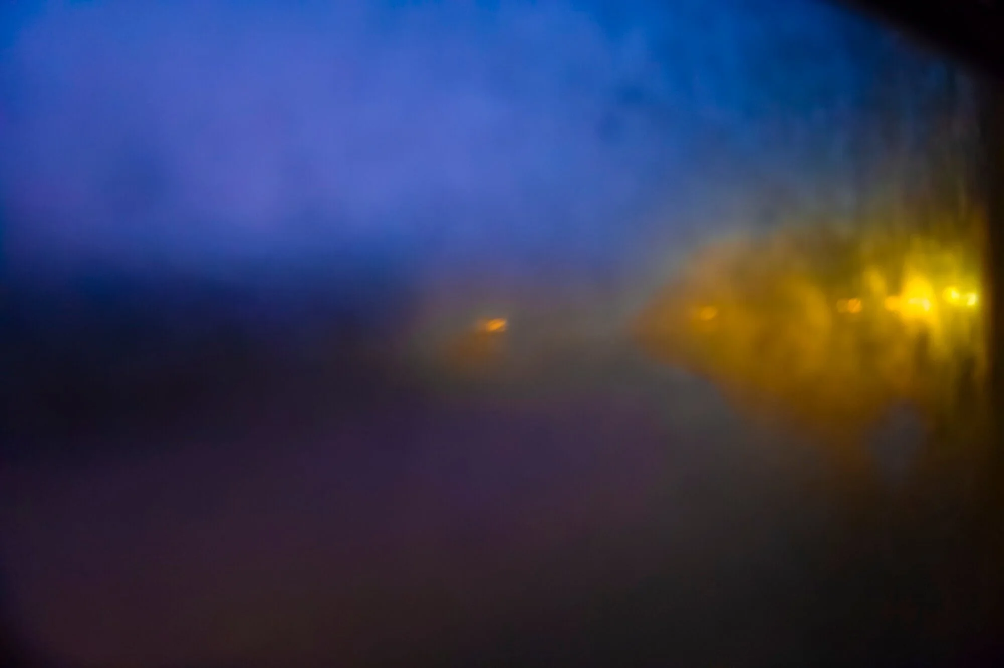 Blurred abstract image with blue, yellow, and purple colors blending together.