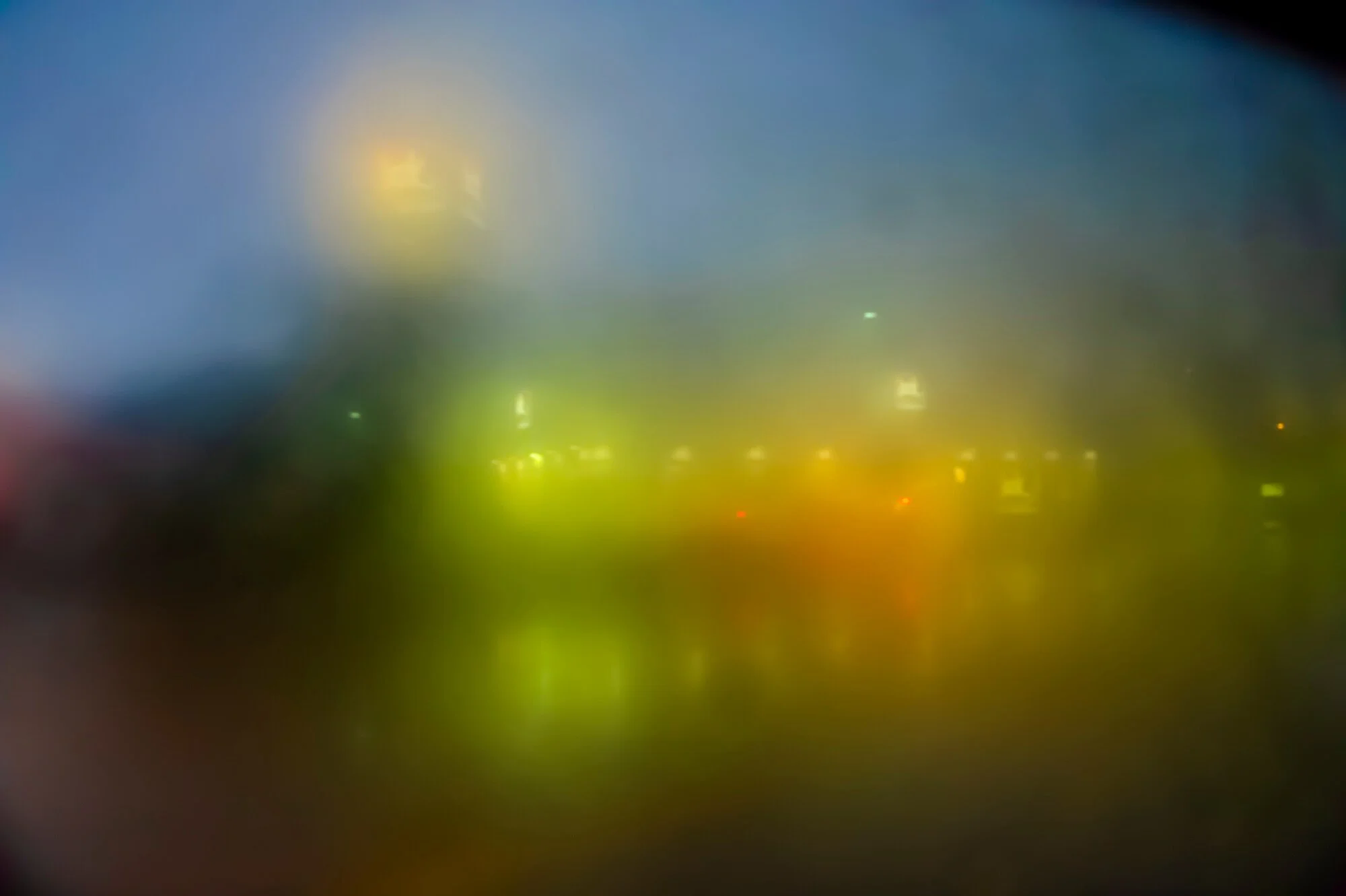 A blurred cityscape at night with indistinct lights and structures.