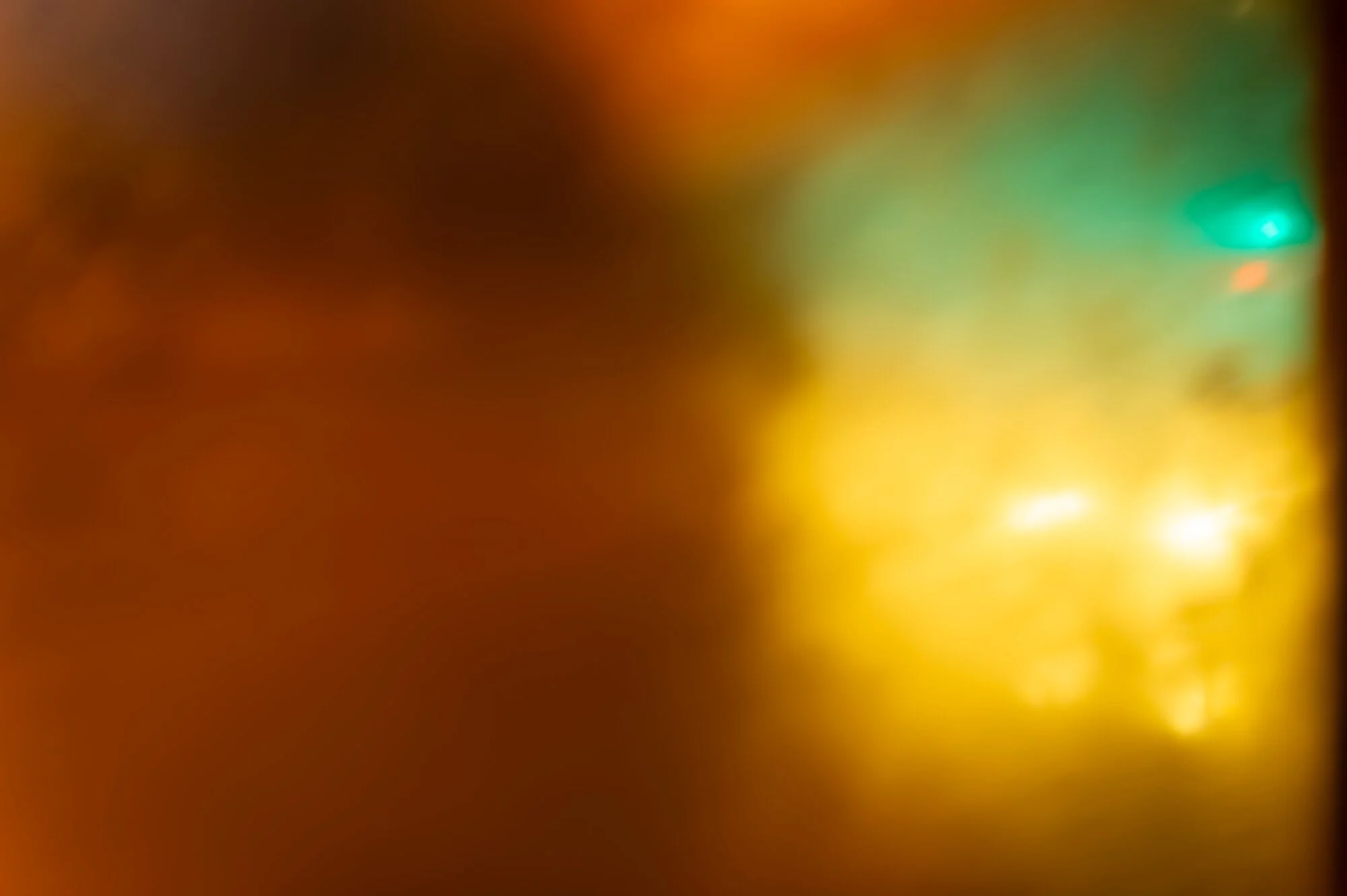 The image is blurry and out of focus, showing a mix of warm colors like orange and yellow, with some hints of green and blue, but details are not distinguishable.